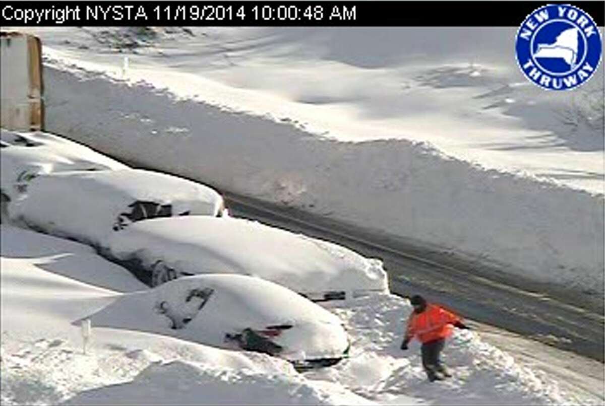 In this photo from a surveillance camera operated by the New York State Thruway Authority, a person climbs through piles of snow next to abandoned vehicles on the Thruway, near Lackawanna, N.Y., Wednesday, Nov. 19, 2014. A 132-mile stretch of the state Thruway in western New York remains closed as authorities continue their efforts to rescue motorists stranded on a Buffalo-area section of the highway. (AP Photo/New York State Thruway Authority)