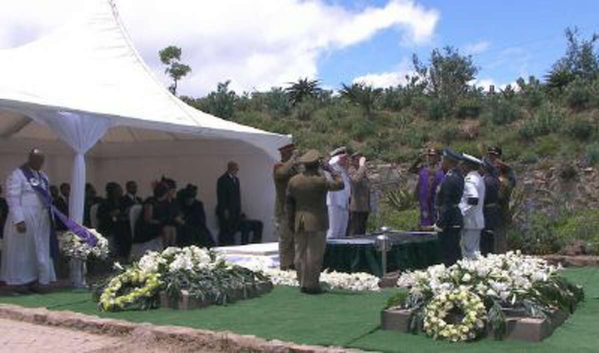 Mandela family members watch and military officers salute as former South African President Nelson Mandela's casket is lowered into his burial site following his funeral service in Qunu, South Africa, Sunday, Dec. 15, 2013.