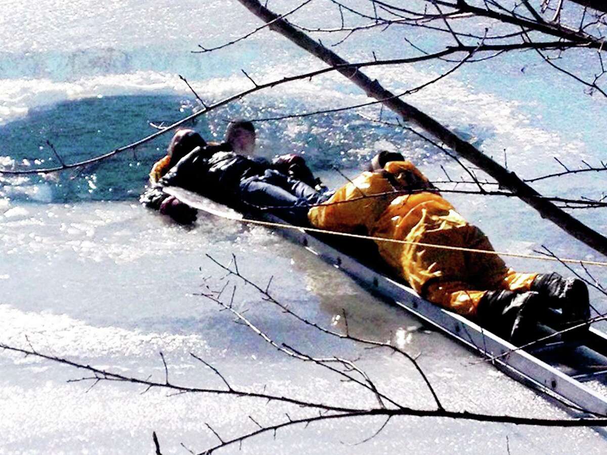 contributed photos - West Haven Fire Department A 70-year-old man fell through the ice on Phipps Lake outside his home at 52 Woody Lane. West Haven firefighters used a flat-bottom boat and ladder to get him out.