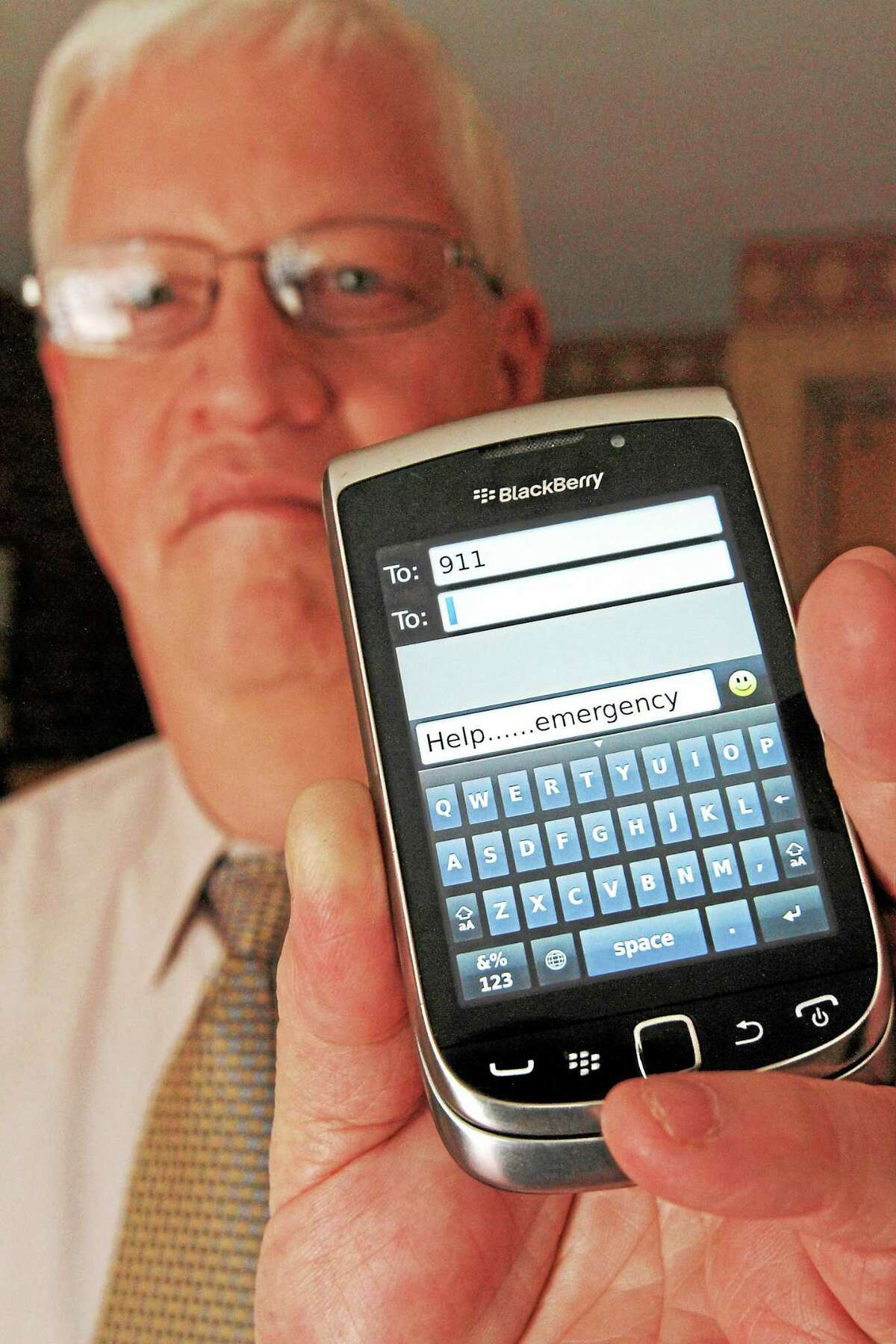 In this April 18, 2012 photo, David Tucker, executive director of Vermont’s Enhanced 911 Board, holds a smartphone in Montpelier, Vt. Tucker says the state is the first in the country where customers of the four major wireless carriers can send text messages to 911. As of Monday, May 19, 2014, T-Mobile customers in Vermont are now able to text 911. Verizon, AT&T and Sprint began the service earlier.