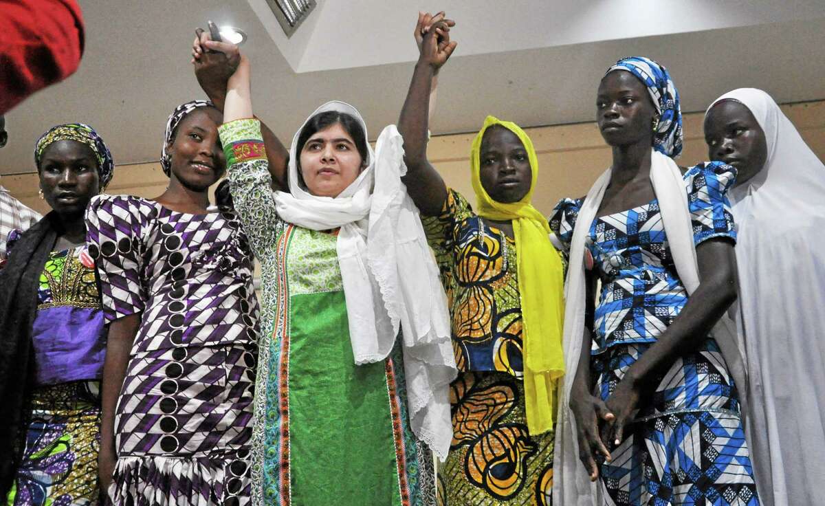 Pakistani activist Malala Yousafzai, centre, raises her hands with some of the escaped kidnapped school girls of government secondary school Chibok during a news confrence, in Abuja, Nigeria, Monday, July 14, 2014. Yousafzai on Monday won a promise from Nigeriaís leader to meet with the parents of some of the 219 schoolgirls held by Islamic extremists for three months. Malala celebrated her 17th birthday on Monday in Nigeria with promises to work for the release of the girls from the Boko Haram movement.