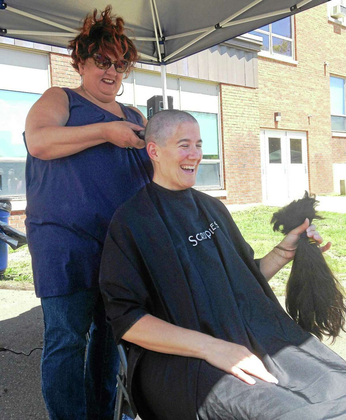 Joanne Poffenberger, a West Haven High School science teacher, holds the hair that stylist Teddi McKenna, of Teddi & Archell a Salon in West Haven, shaved off her head at Sundayís Westie Day of Hope fundraiser at West Haven High School.