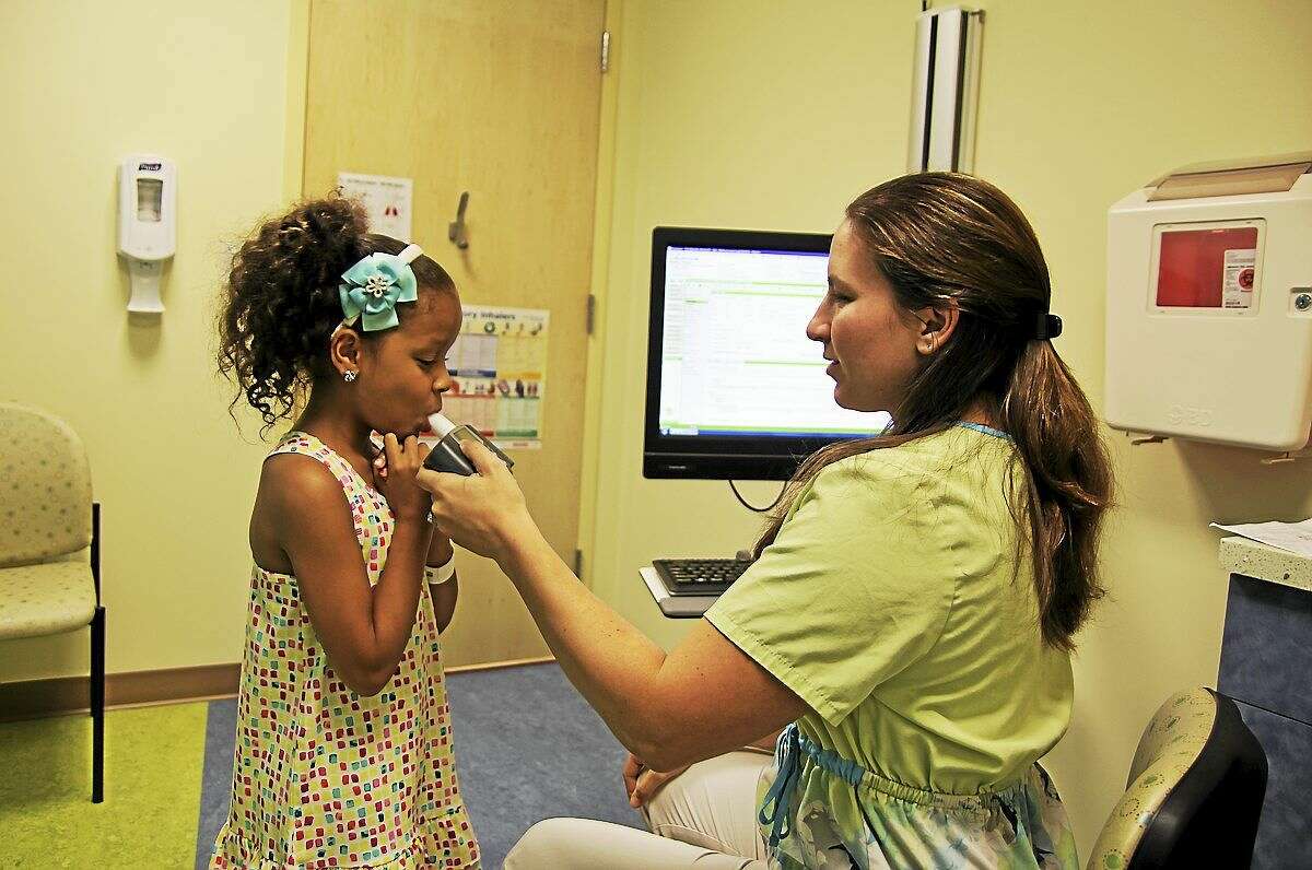 Megan Judkins, a nurse at Dr. Jabob Hen’s pediatric pulmonology practice in Trumbull, helps Ariana Gomez, 7, of Ansonia, test her breathing.