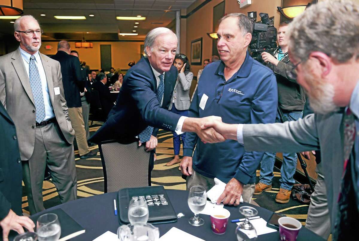 Connecticut gubernatorial candidate Tom Foley, center, shakes hands with John Simone of the CT Main St. Center at a Transportation Forum in North Haven Monday.