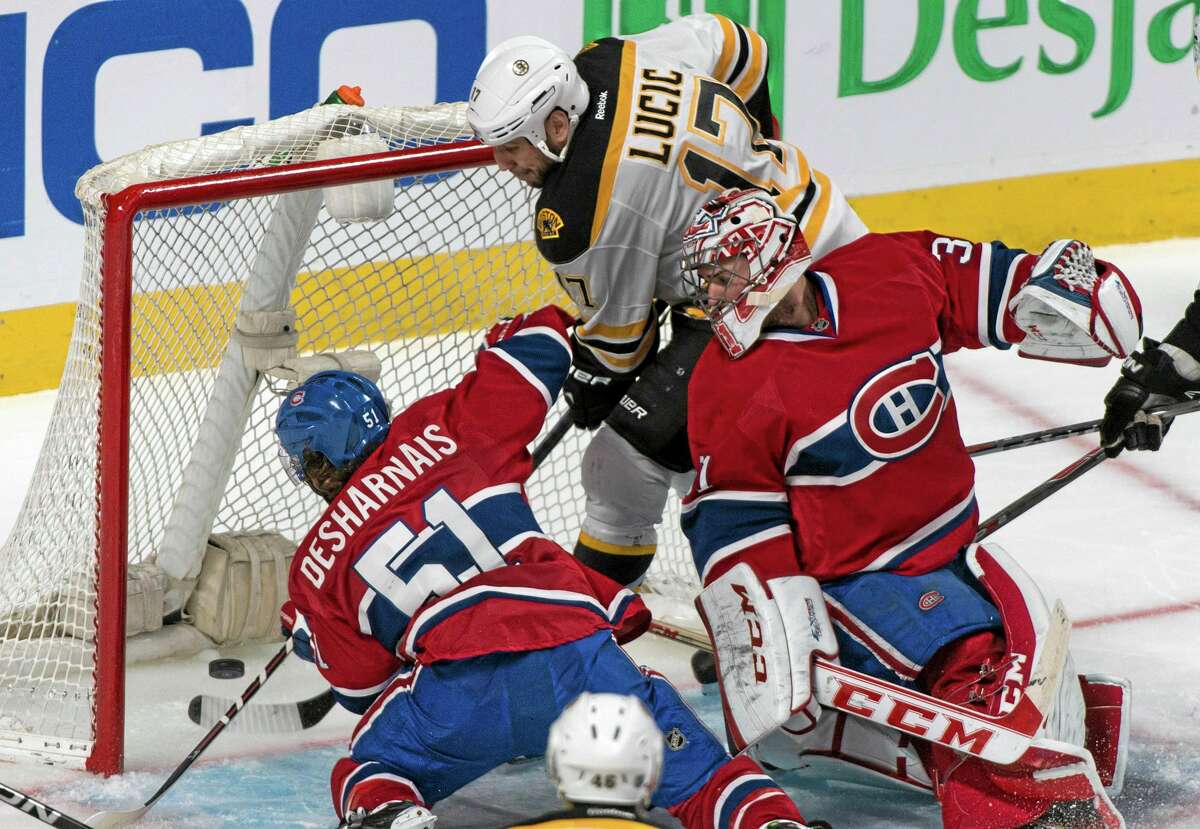 The Canadiens’ David Desharnais (51) manages to keep the puck from crossing the line as goalie Carey Price and the Bruins’ Milan Lucic (17) look on during the third period of Game 6 on Monday in Montreal.