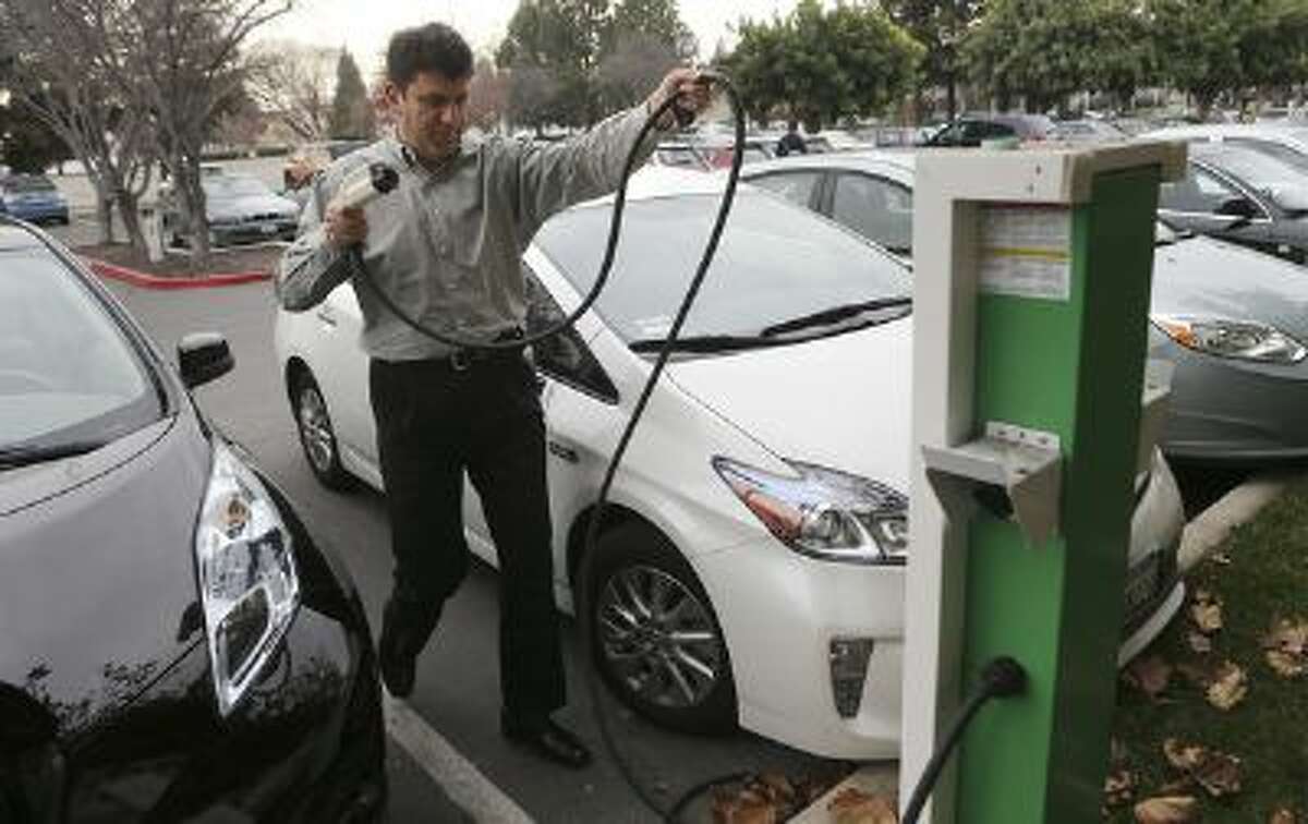 Rabih Sabbagh prepares to move his Prius as Satyen Kansara, right, goes to move his car into the Sabbagh's charging station at Infoblox in Santa Clara, Calif. on Monday, Jan. 6, 2014.