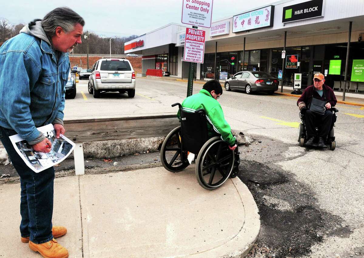 (Mara Lavitt ó New Haven Register) January 20, 2013 Seymour Seymour town engineer Jim Galligan, left, marks a deteriorating curb cut in downtown Seymour as his son Kevin (of North Branford) tries to negotiate it while Joseph Luciano of Seymour watches.