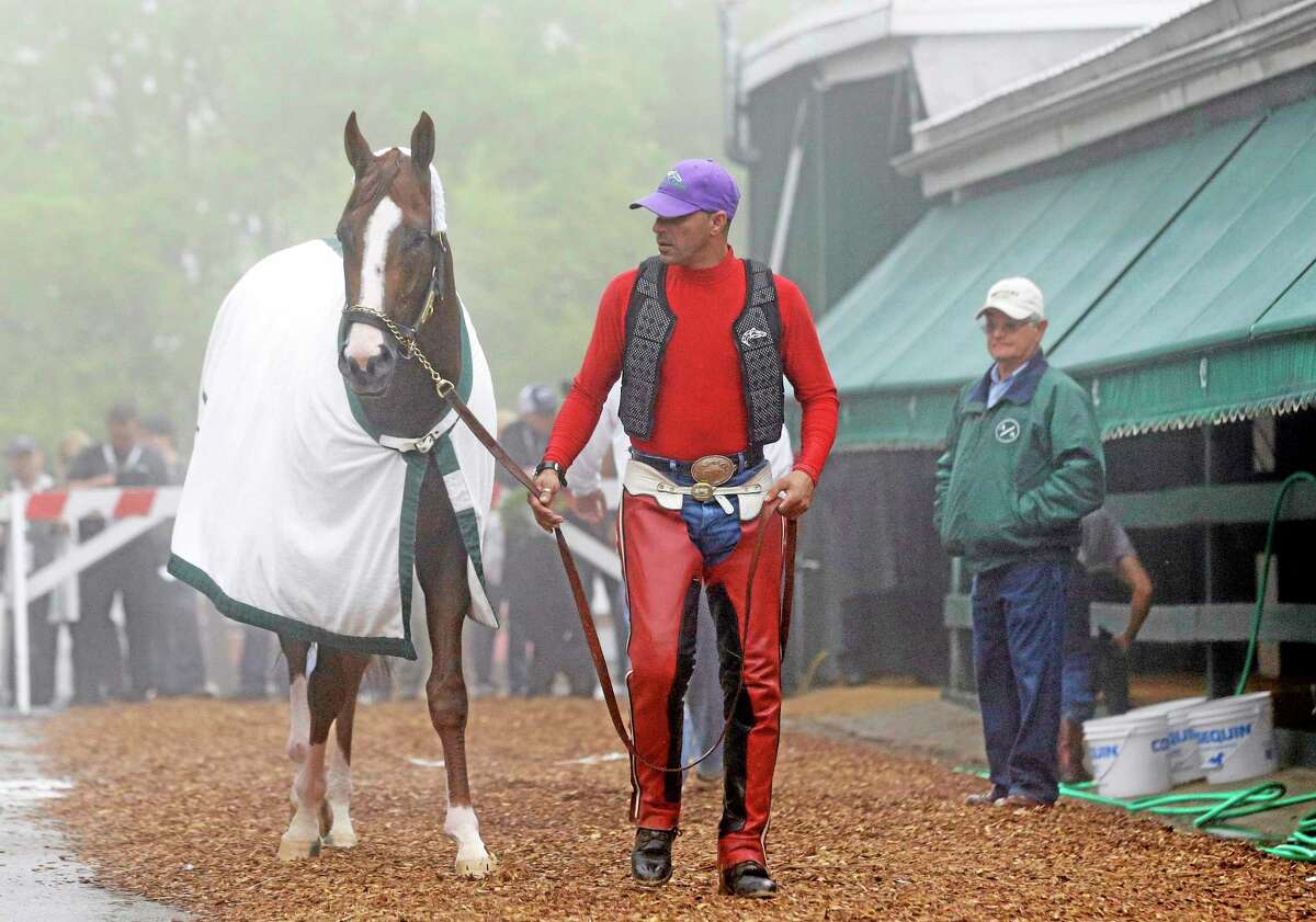 Exercise rider Willie Delgado, center, leads Kentucky Derby winner California Chrome to his stable as trainer Art Sherman, right, watches after a Thursday workout at Pimlico Race Course in Baltimore. The Preakness Stakes is Saturday.