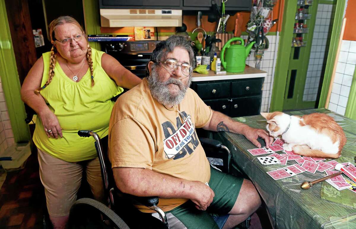 Gordon Hayes, center, who has contracted hepatitis C, is photographed with his wife, Caroline, at home in Ansonia. The cat’s name is Bubba.