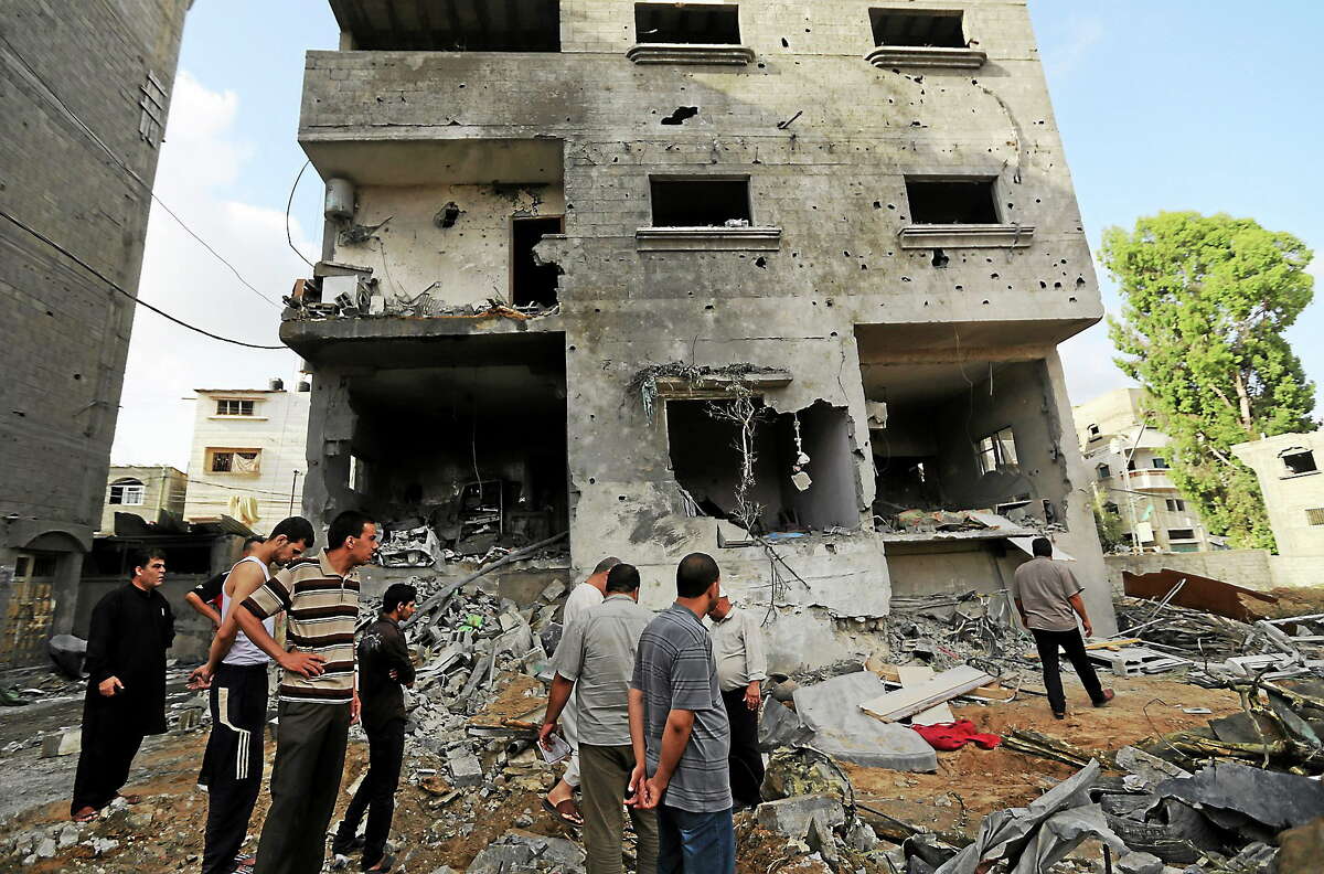 Palestinians gather outside the damaged house of Gaza’s police chief Taysir al-Batsh after it was hit by an Israeli missile strike in Gaza City on July 13, 2014.