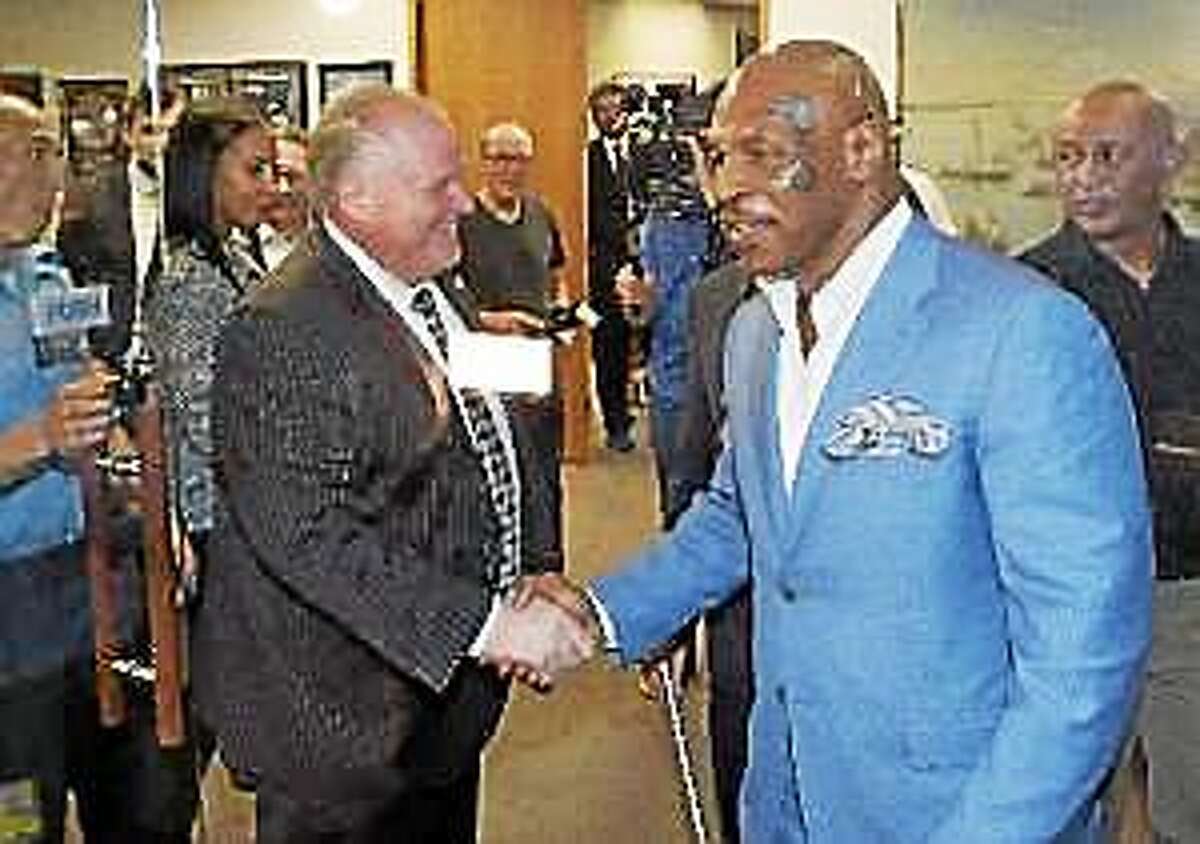 Toronto Mayor Rob Ford, center, shakes hands with former heavyweight boxing champion Mike Tyson at City Hall in Toronto on Tuesday, Sept. 9, 2014.