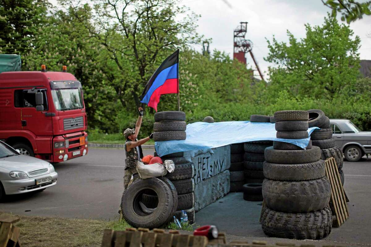 Pro-Russian insurgents with the self-proclaimed Donetsk People's Republic man a checkpoint by the Karl Marx coal mine seen in the background near Korsun, a small town about 30 km north-east from Donetsk, eastern Ukraine, Tuesday, May 13, 2014. The words on the wall of barricades read " No fascism". The Donetsk People's Republic has proclaimed independence from Ukraine after a contentious autonomy referendum Sunday that has been rejected by the government and the international community. (AP Photo/Alexander Zemlianichenko)
