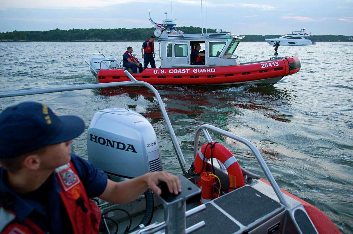In this photo taken July 12, 2014, Seaman Robert Von Bargen, left, and other personnel on U.S. Coast Guard response boats out of Station Kings Point, N.Y., patrol near Glen Island in western Long Island sound near New Rochelle, N.Y. as they work to keep boaters at a safe distance from barge that would soon be the water base of a fireworks display. A wedding celebrated on Glen Island featured fireworks, and the Coast Guard engaged in keeping a safe zone for boaters around the pyrotechnics.
