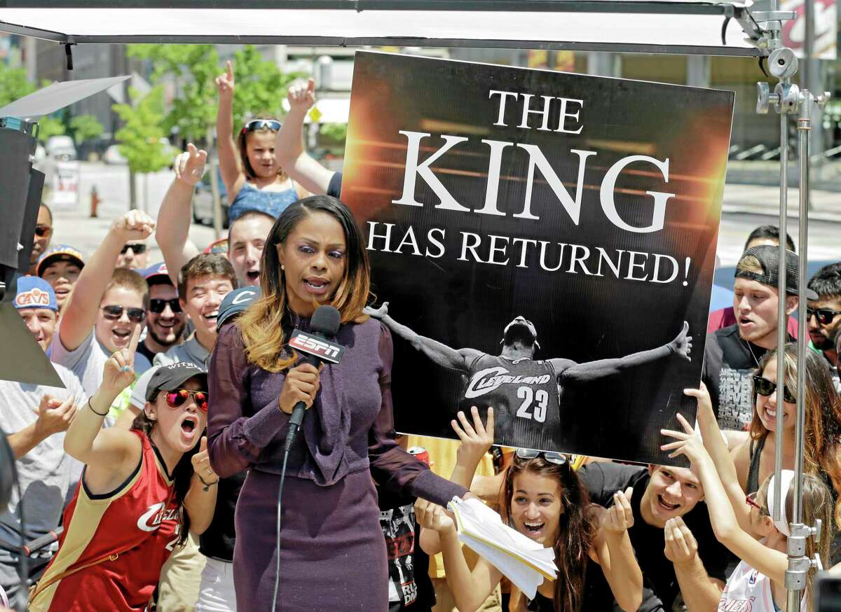 Fans whoop it up behind an ESPN reporter outside Quicken Loans Arena in Cleveland after LeBron James announced he would return to the Cavaliers on Friday.