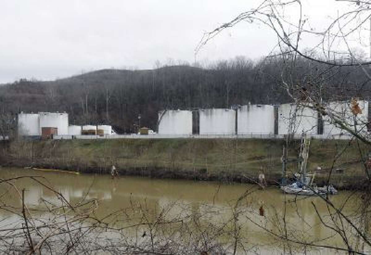 In this Monday, Jan. 13, 2014, file photo, workers,left, inspect an area outside a retaining wall around storage tanks where a chemical leaked into the Elk River at Freedom Industries storage facility in Charleston, W.Va.