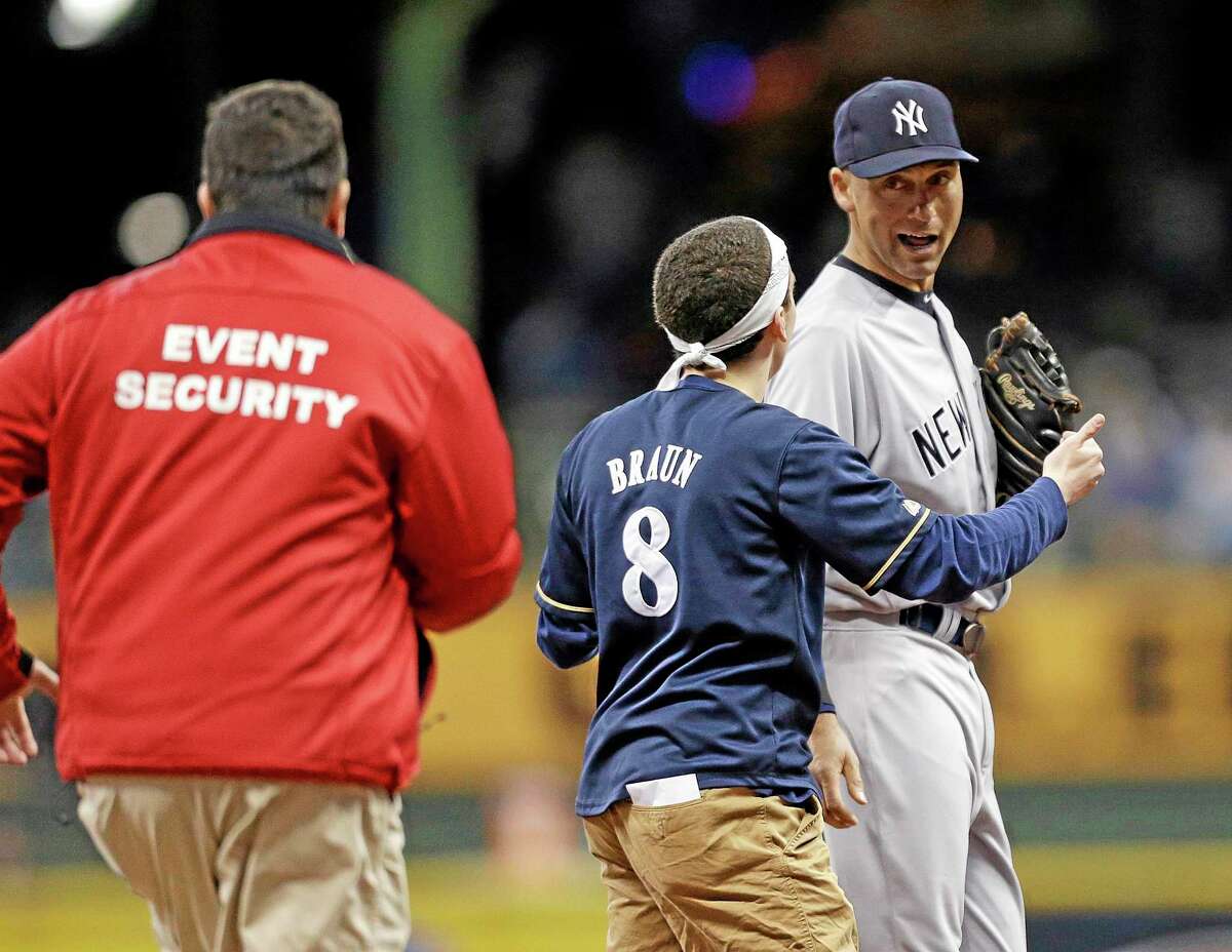 A fan runs out on the field to New York Yankees’ Derek Jeter, right, in the sixth inning of Friday’s game against the Milwaukee Brewers.