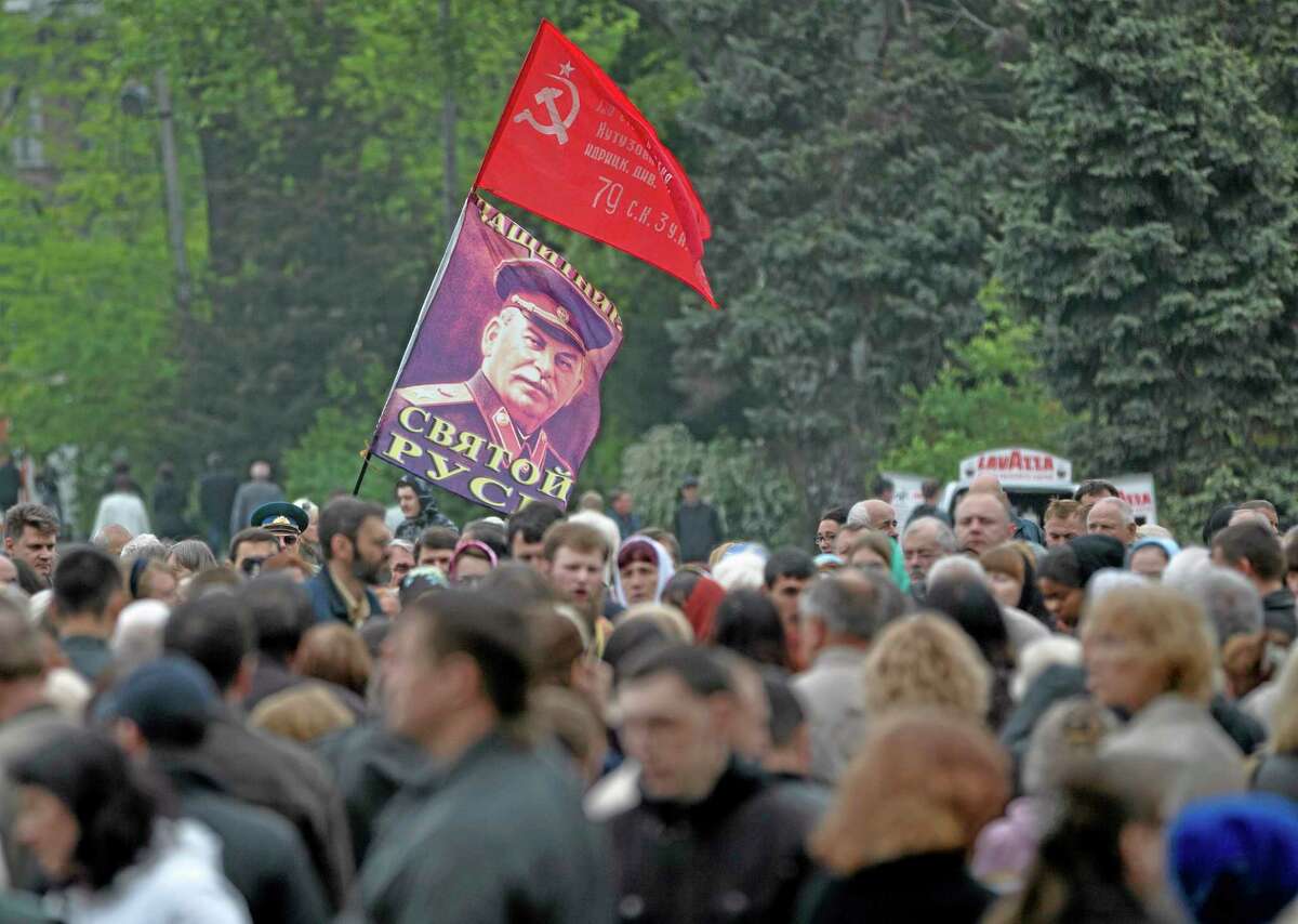 A WWII Soviet flag replica and a portrait of former Soviet leader Joseph Stalin fly above crowds gathered for a religious service in memory of the the victims of last week's trade union building blaze in Odessa, Ukraine, Saturday, May 10, 2014. The Black Sea port of Odessa was last week rocked by violent clashes between pro-Russian forces and supporters of the central government that left nearly 50 people dead. (AP Photo/Vadim Ghirda)