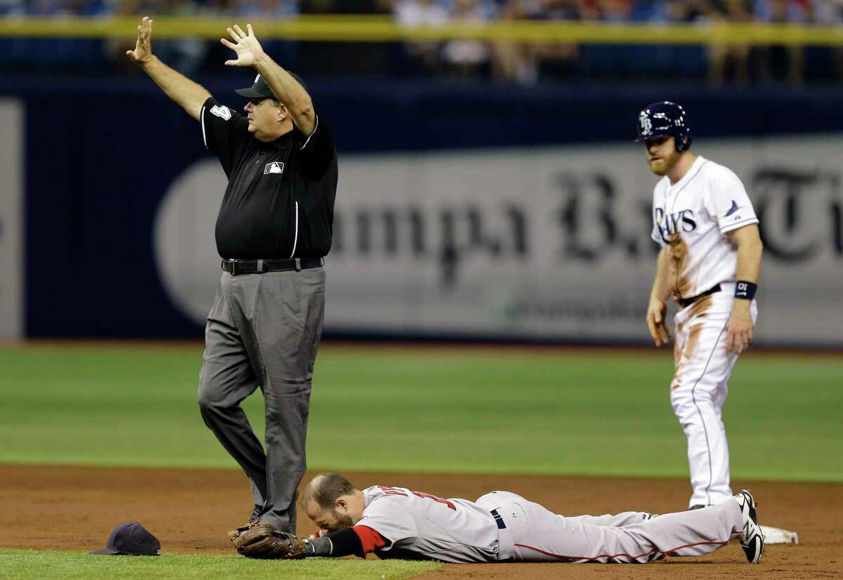 Boston Red Sox second baseman Dustin Pedroia lies injured after colliding with the Tampa Bay Rays’ Logan Forsythe on Saturday in St. Petersburg, Fla.