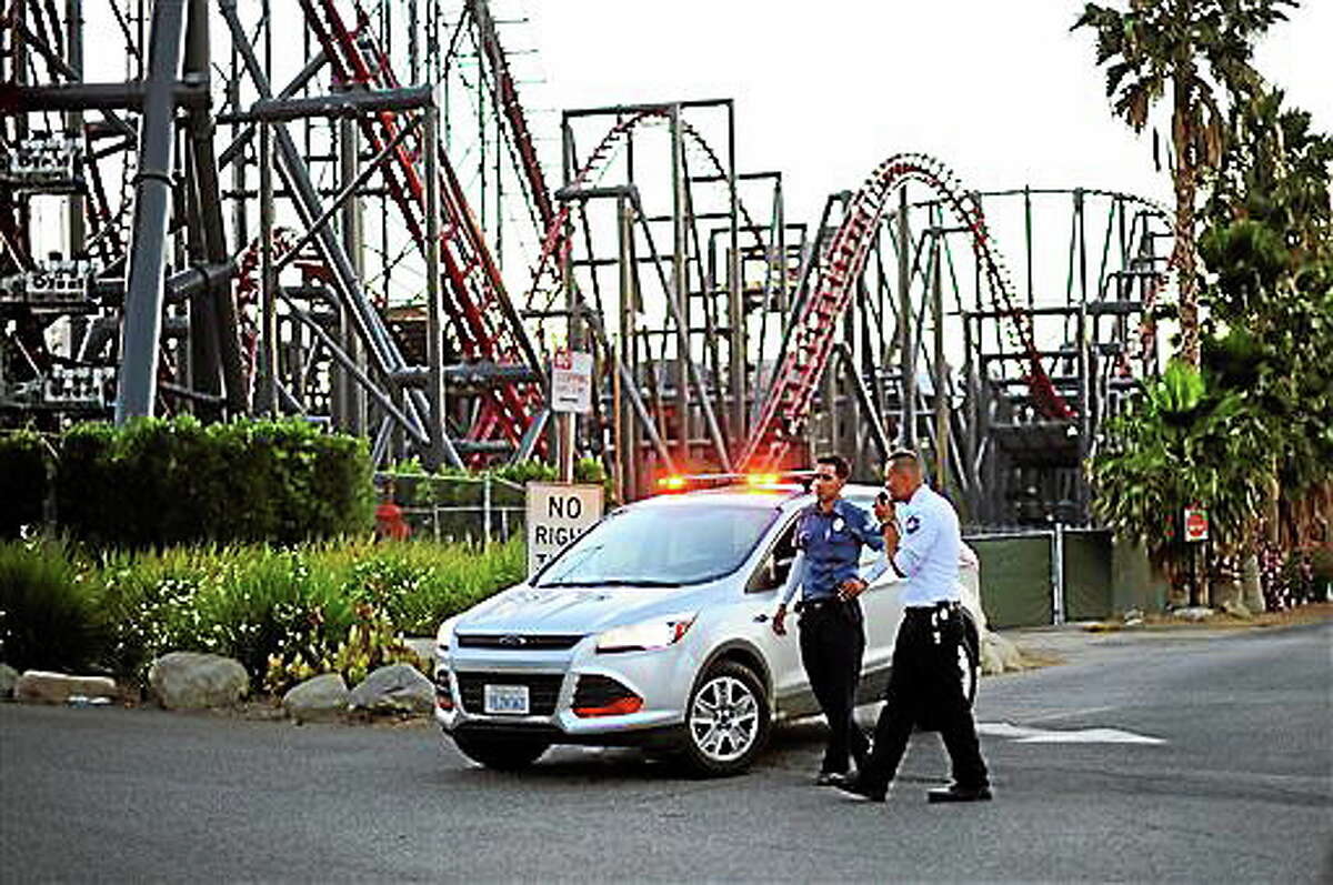 Members of the Six Flags Magic Mountain amusement park security staff monitor the situation at the exit of the park after riders were injured on the Ninja coaster Monday, July 7, 2014, in Valencia, Calif. The roller coaster hit a tree branch dislodging the front car, leaving four people slightly injured and keeping nearly two dozen summer fun-seekers hanging 20 to 30 feet in the air for hours as day turned to night. Two of the four people hurt on the Ninja coaster were taken to the hospital as a precaution, but all the injuries were minor, fire and park officials said.