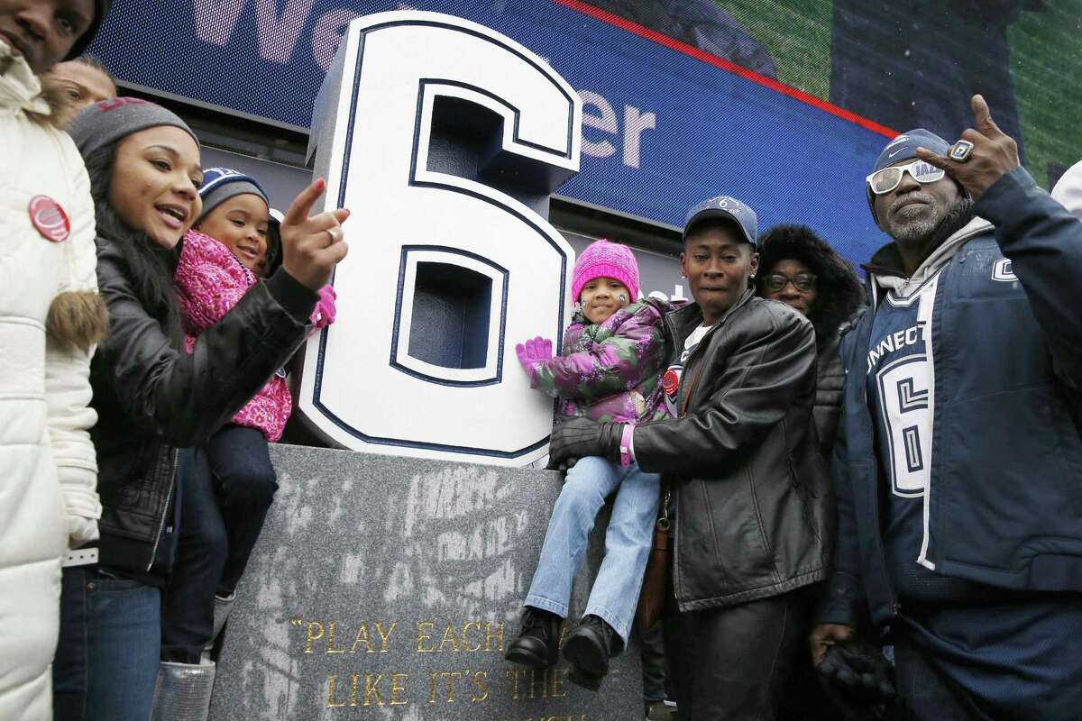 Relatives of former UConn player Jasper Howard, including step-father Herny Williams, right, grandmother Vicki Ross, second from right, mother Joangila Howard, third from right, and fiancée Daneisha Freeman, second from left, gather around a memorial to Howard after its unveiling during halftime of the Huskies’ 37-29 win over Central Florida on Saturday at Rentschler Field in East Hartford.
