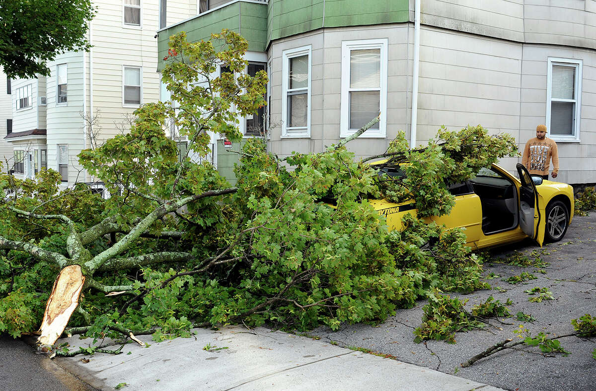 Angel Alcoba looks at the damage to his 2007 Dodge Charger in his driveway on Windham Street, Monday, Sept. 1, 2014, in Worcester, Mass. A tree limb smashed through the back window of the car during Sunday night's storm. "I thought the whole house was coming apart," Alcoba said about the storm. The National Weather Service confirmed that Sunday night's storm in the Grafton Hill and Vernon Hill neighborhoods was a tornado. (AP Photo/Worcester Telegram & Gazette, Rick Cinclair)