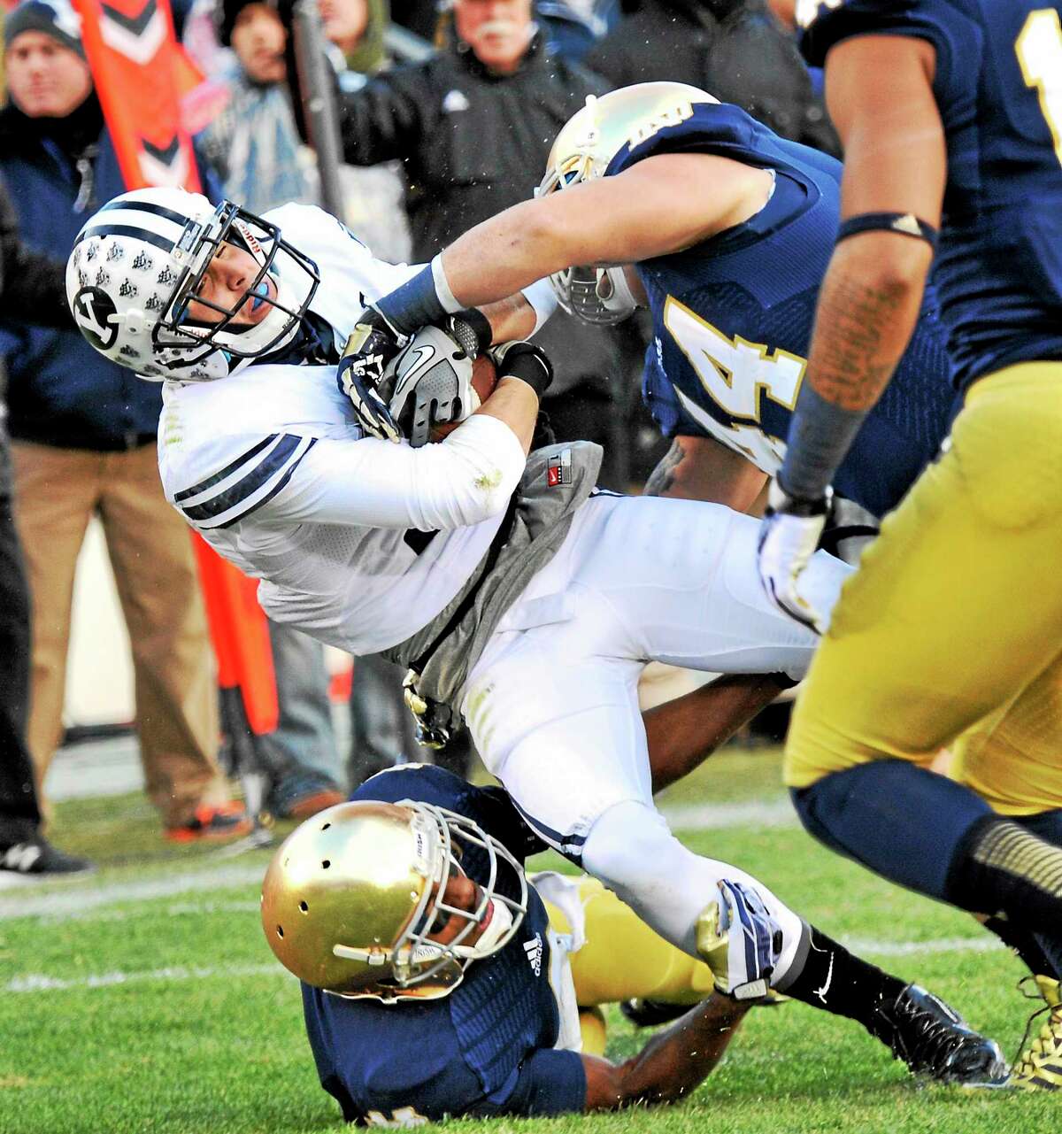 BYU wide receiver Skyley Ridley is tackled by Notre Dame linebacker Carlo Calabrese, right, and cornerback KaiVarae Russell during a Nov. 23, 2013, game in South Bend, Ind. Calabrese says new UConn football coach Bob Diaco will bring a winning culture to the Huskies.