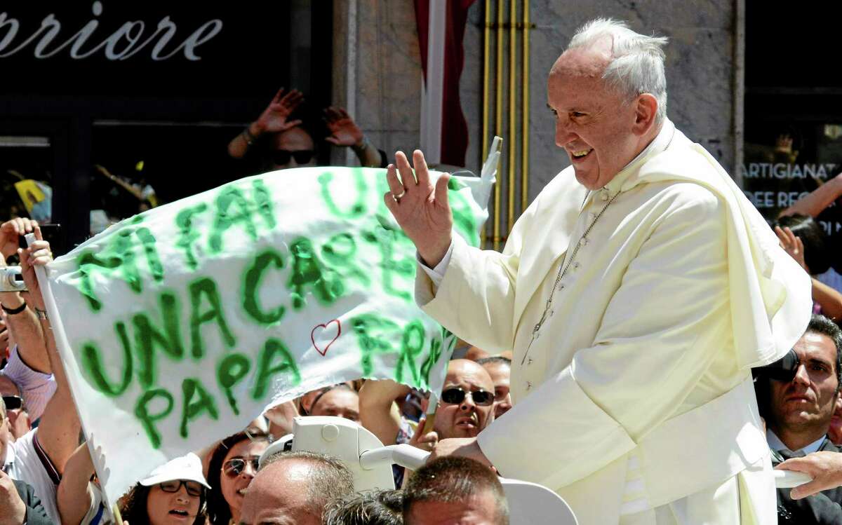 Faithful hold up a banner reading in Italian, “Can you caress me Pope Francis” as the pontiff arrives Saturday at Campobasso Cathedral in Italy.
