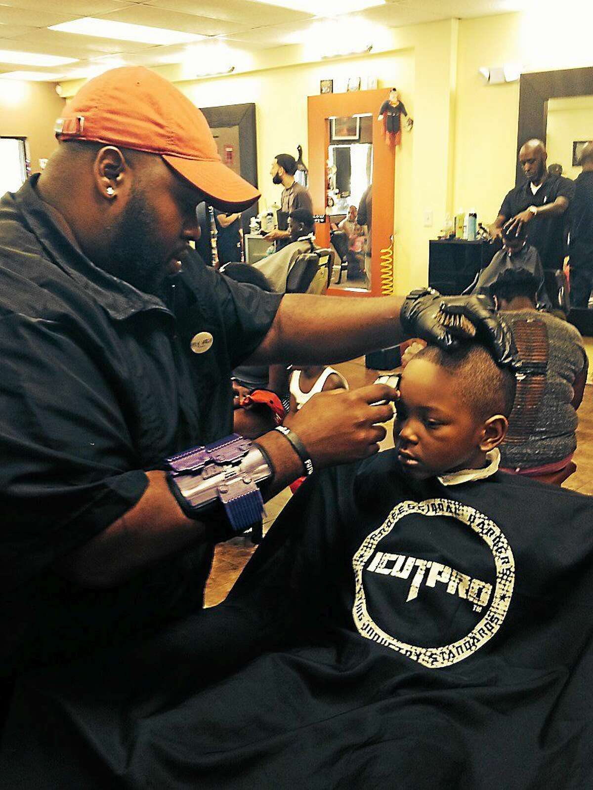 Barber Ephriam Green of Transformerz Barbershop gives a back-to-school haircut to Ahmeer Kamara, 5.