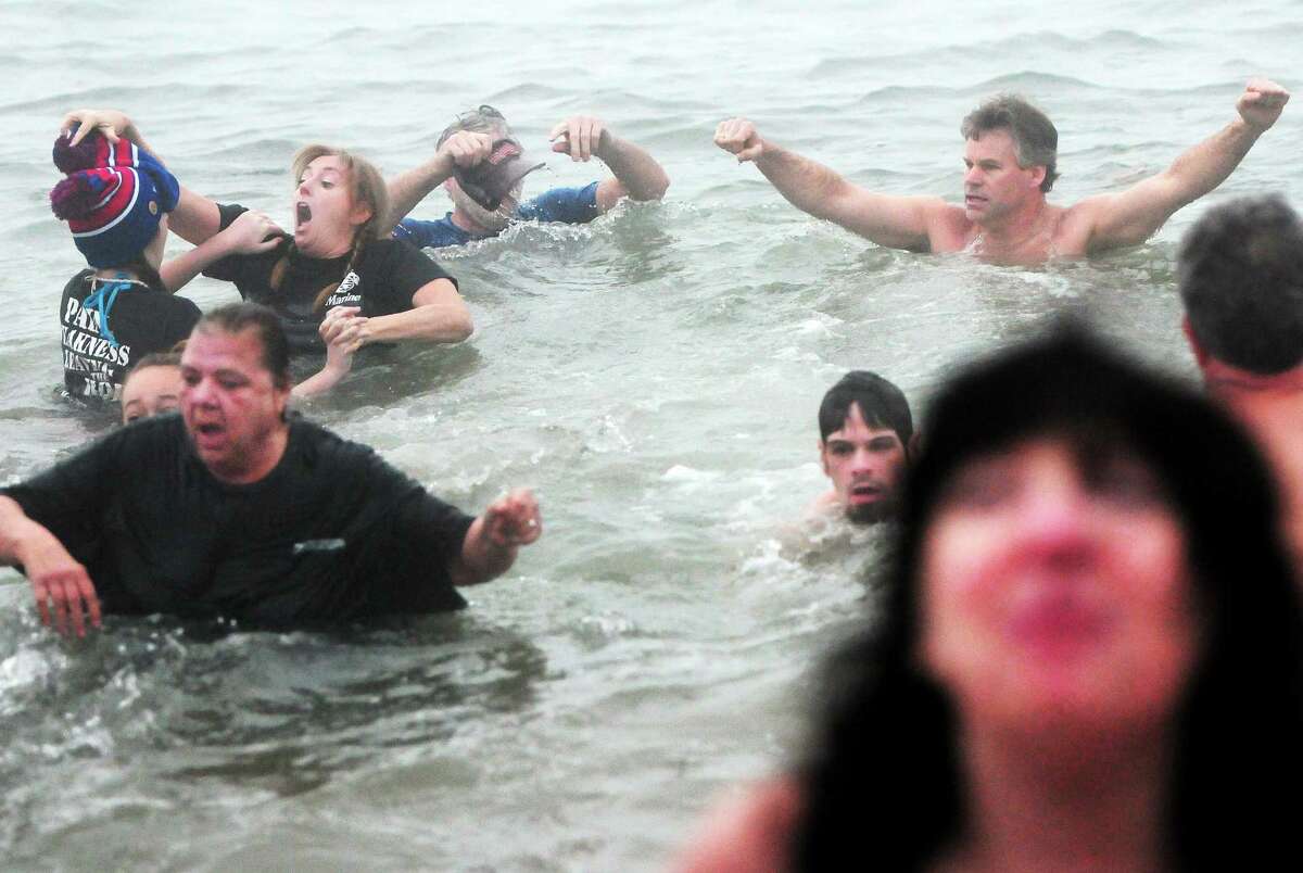 Participants react to the cold water as they participate in the 14th annual Icy Plunge for the Cure Saturday at the beach behind the Savin Rock Conference Center in West Haven.