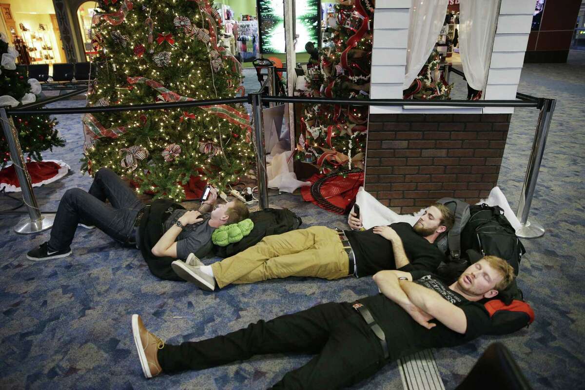 From left, Nick Burton, Clancy Sloan and Graham Anderson rest while waiting for their flight at McCarran International Airport Sunday, Dec. 21, 2014, in Las Vegas. (AP Photo/John Locher)