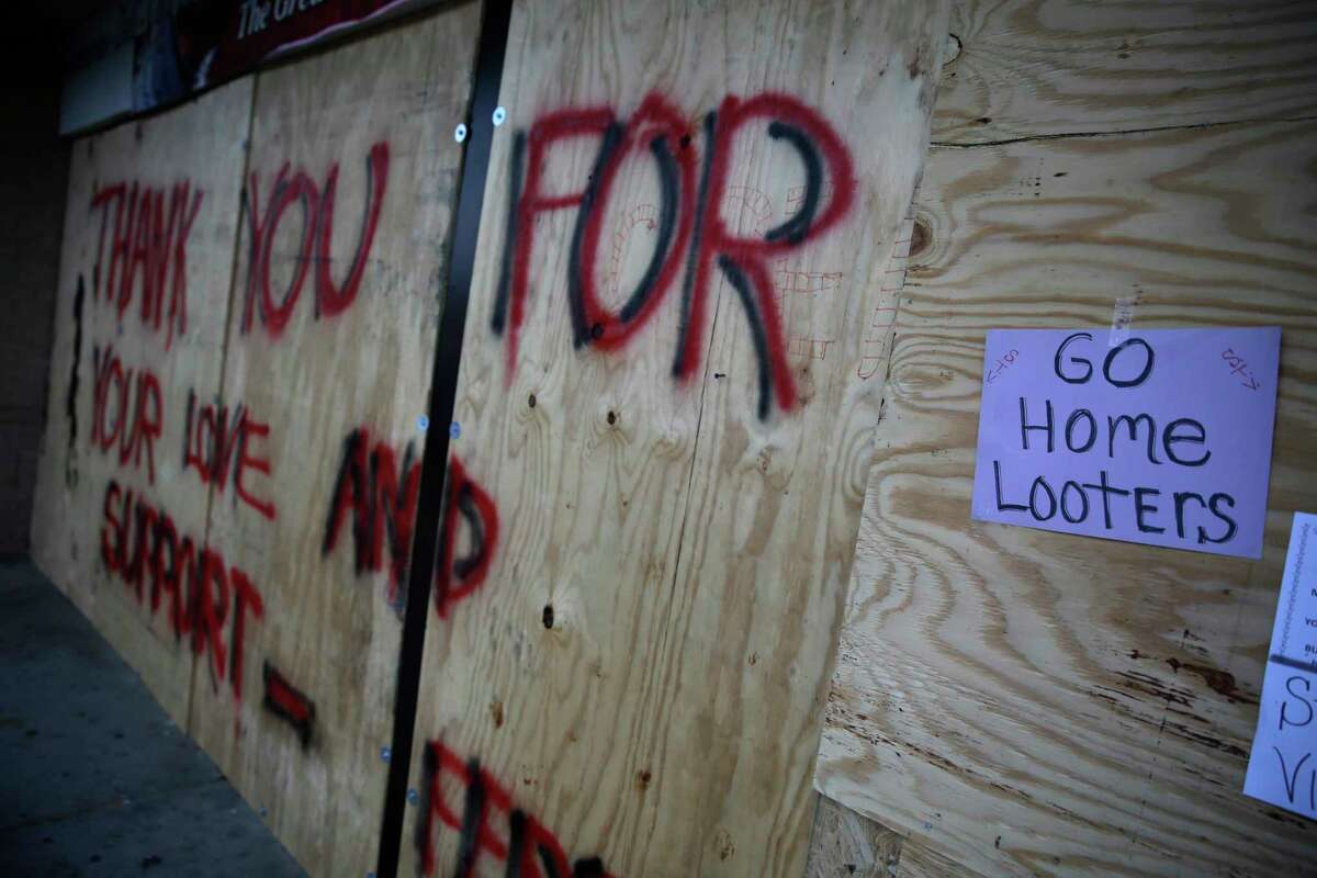 FILE - in this Aug. 18, 2014 file photo, a message is written on a boarded up liquor store in Ferguson, Mo. Businesses that were victimized by looting are slowly coming back as signs of healing are beginning to dot the area. (AP Photo/Jeff Roberson, File)