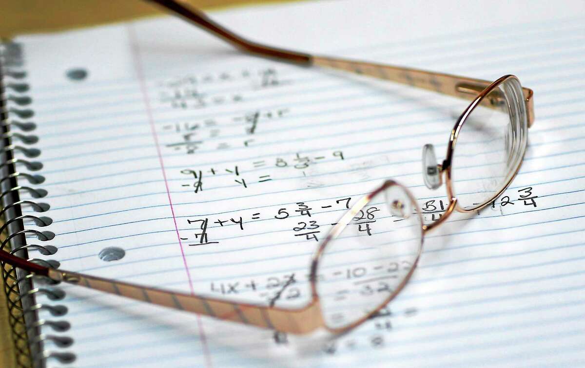 A student’s glasses sitting on a notebook containing math exercises.