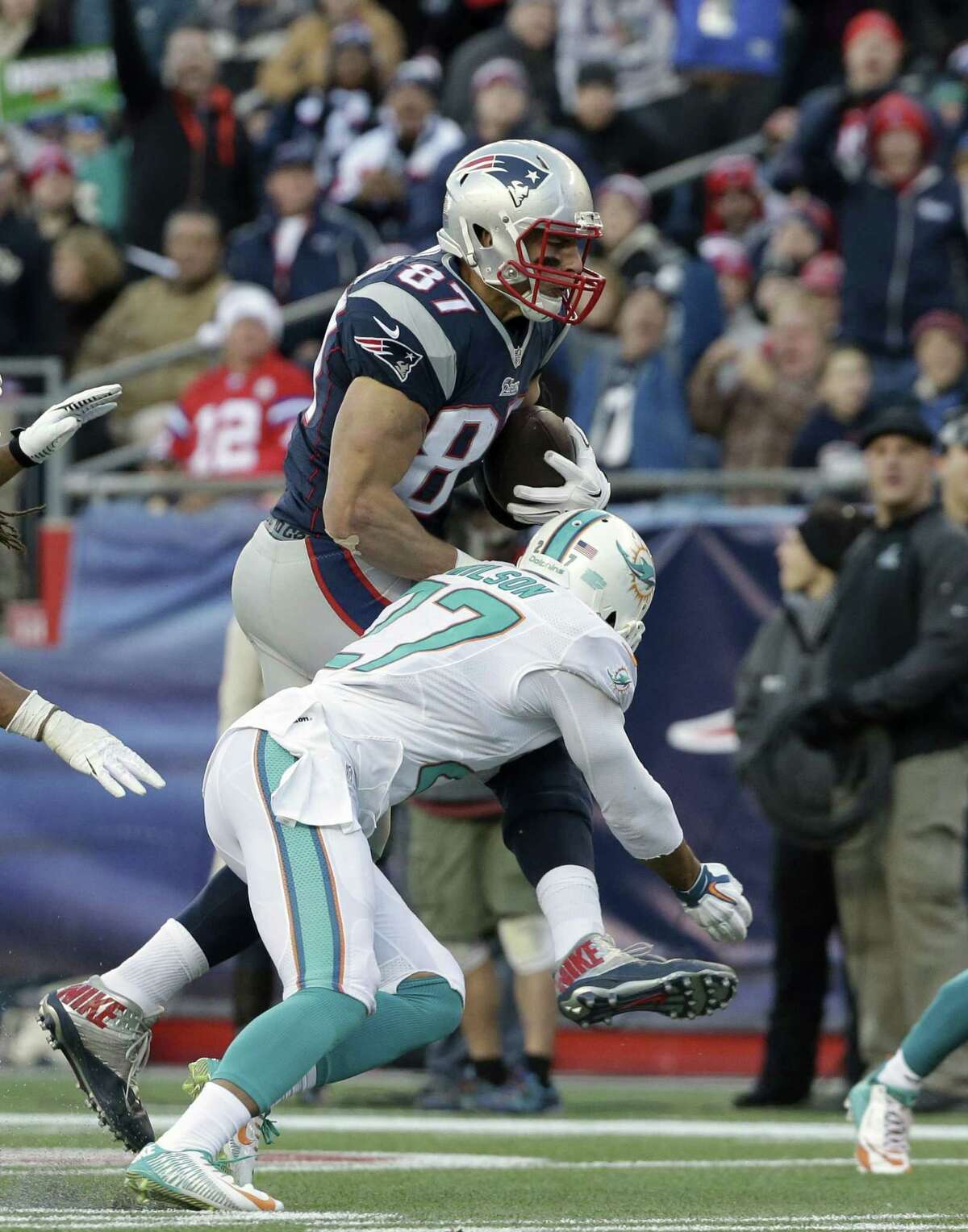 New England Patriots tight end Rob Gronkowski, top, advances the ball while under pressure from Miami Dolphins strong safety Jimmy Wilson, below, in the second half of an NFL football game Sunday, Dec. 14, 2014, in Foxborough, Mass. (AP Photo/Steven Senne)