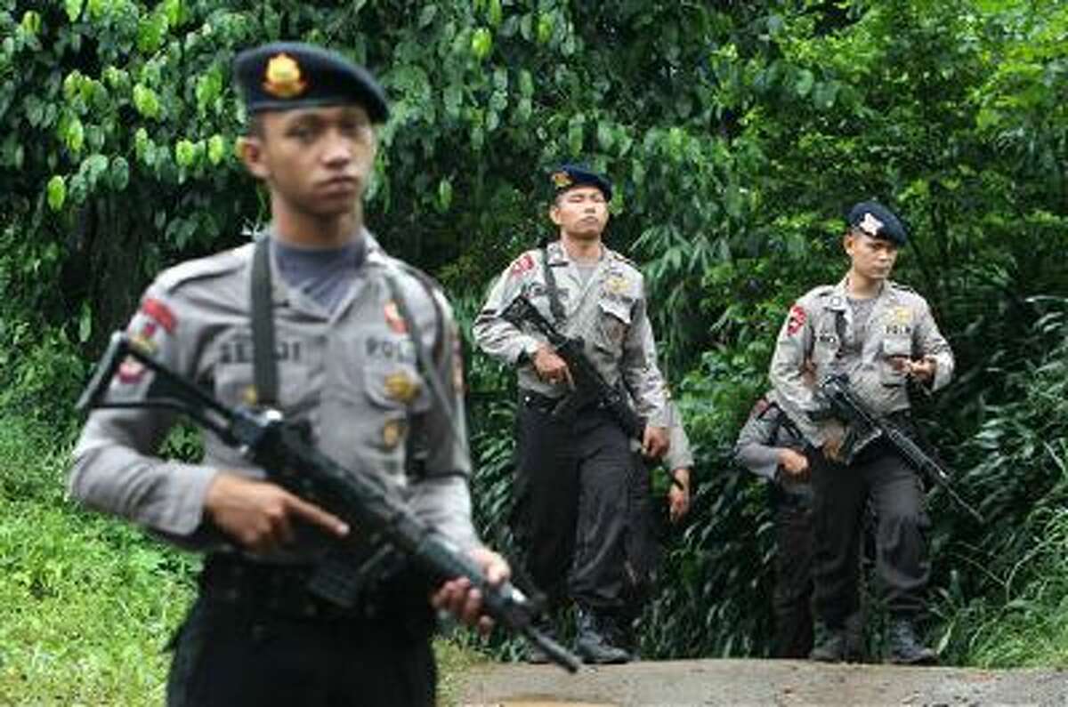 Police officers patrol the area near a house Wednesday that was used as a hideout by suspected militants following an overnight raid in Ciputat, Indonesia. Indonesia's elite anti-terrorism squad shot and killed six suspected militants amid New Year's Eve celebrations.