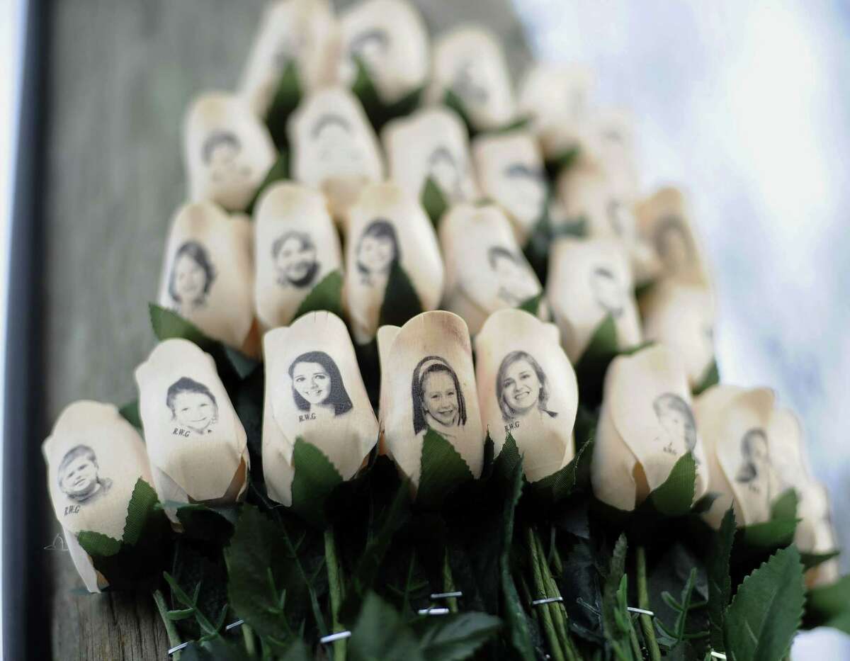 In this Jan. 14, 2013 photo, white roses with the faces of victims of the Sandy Hook Elementary School shooting are attached to a telephone pole near the school on the one-month anniversary of the shooting that left 26 dead in Newtown, Conn.