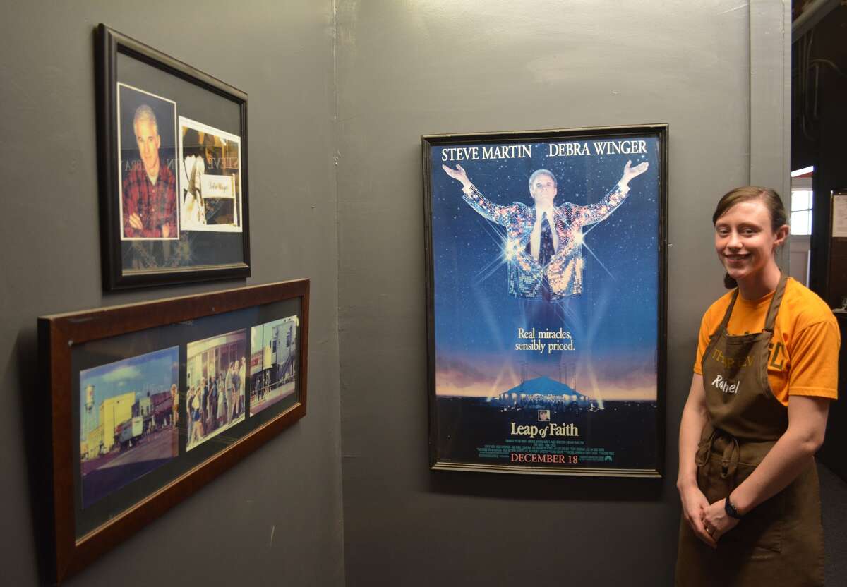 Rachel Bohnet of the Broadway Brew points out the movie poster and photos taken during the filming of the 1992 motion picture “Leap of Faith,” starring Steve Martin and Debra Winger. Much of the movie was filmed at the Brew, then known as The Quick Lunch. A wall in the back hallway of the popular coffee house offers a look back at Plainview’s brush with Tinseltown.