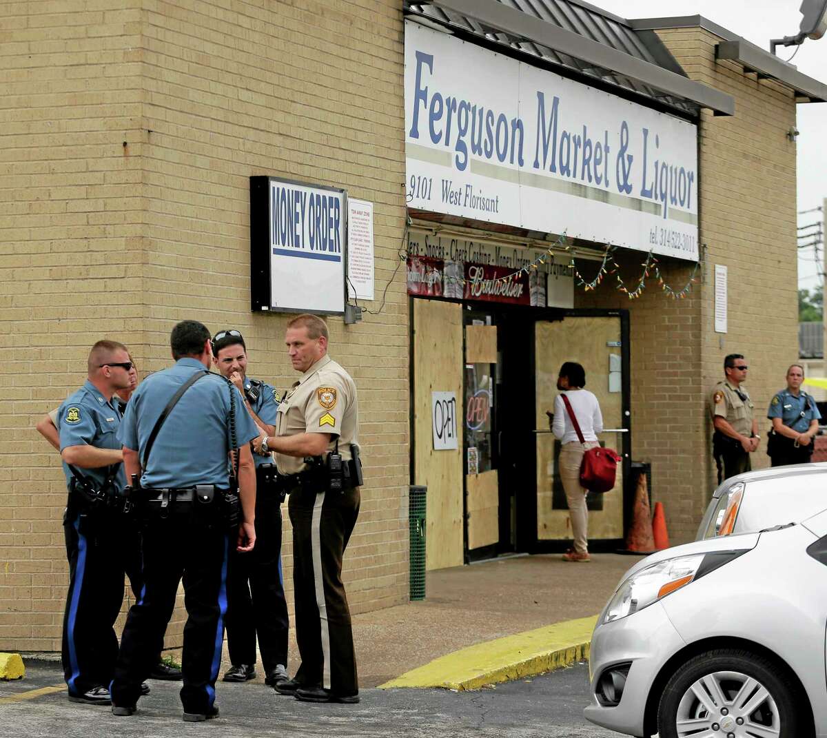 Law enforcement officers stand watch outside a market, Friday, Aug. 15, 2014, in Ferguson, Mo.