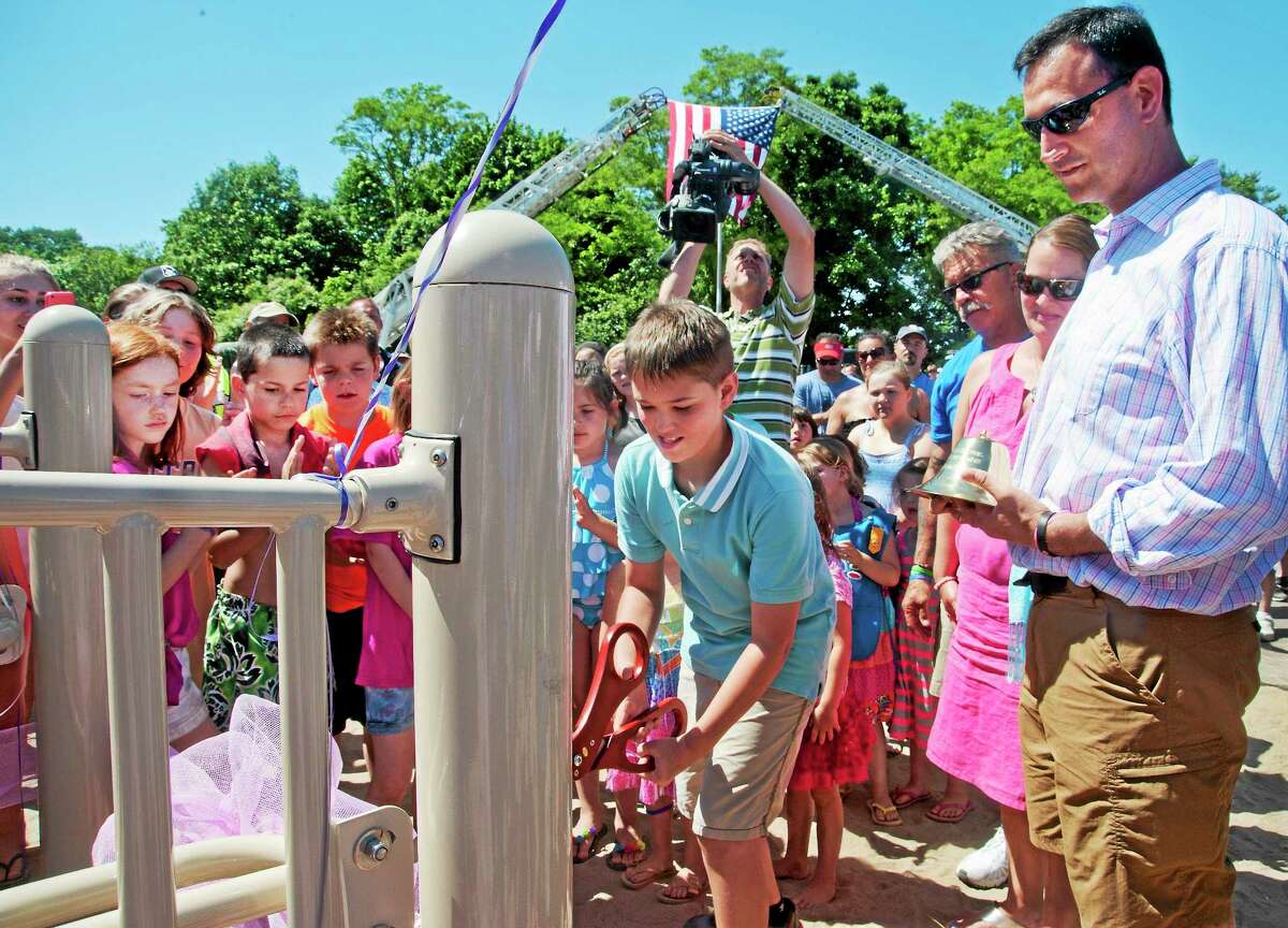 Children crowd around Guy Bacon, brother of Sandy Hook shooting victim, Charlotte Bacon, as he cuts the ribbon to the West Haven playground built in Charlotte’s memory. To the right are parents Joanne and Joel Bacon.