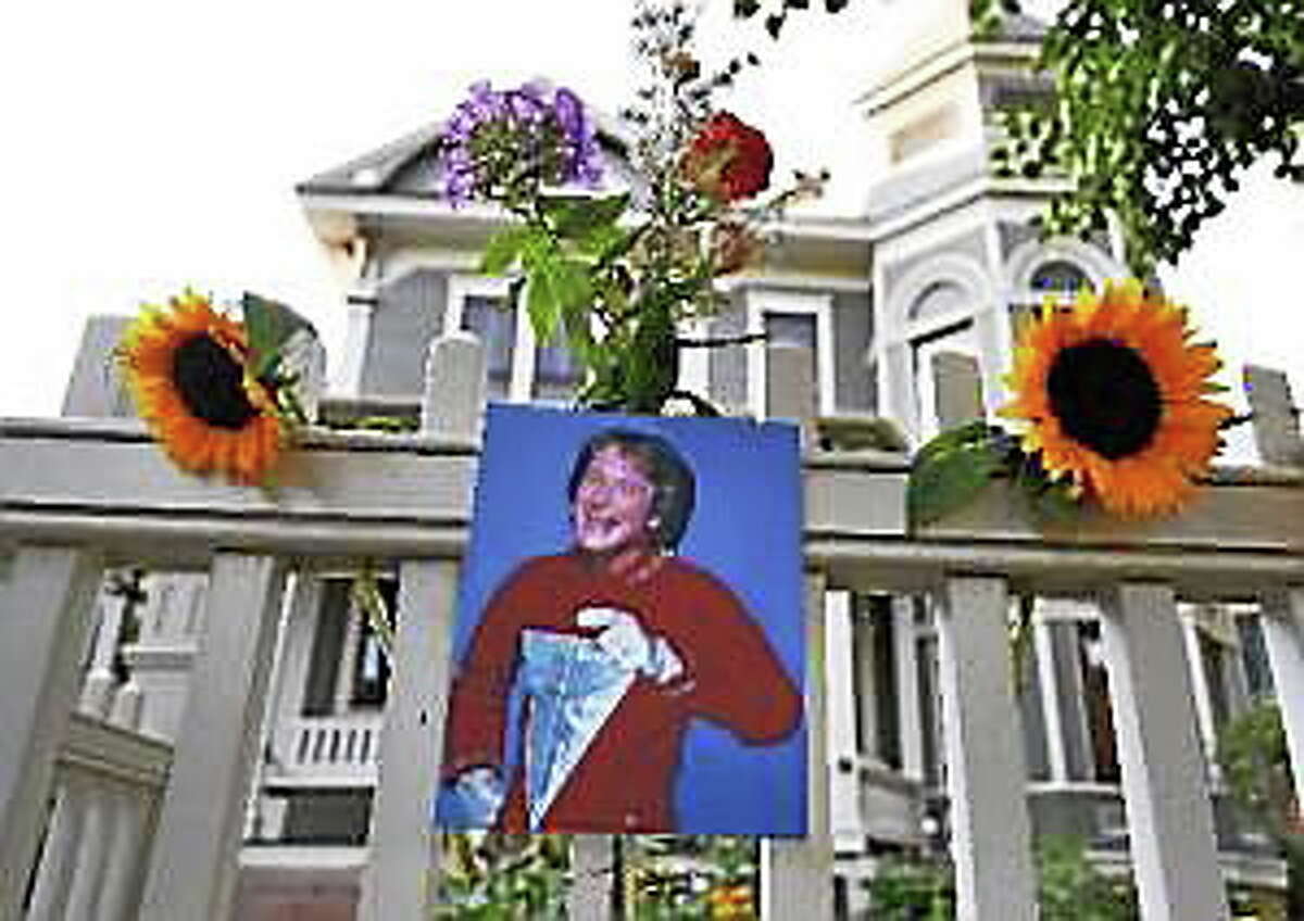 A photo of the late actor Robin Williams as Mork from Ork hangs with flowers left by people paying their respects, in Boulder, Colo., Monday Aug. 11, 2014, at the home where his hit 80’s TV series “Mork & Mindy”, was set.