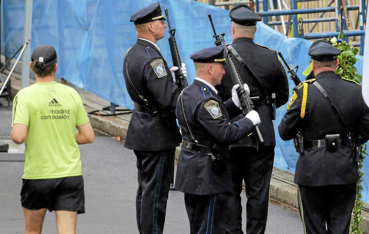 A runner passes as Boston Police honors change their post outside the Marathon Sports store, the site of the first of two bombs that exploded near the finish line of the 2013 Boston Marathon, Tuesday, April 15, 2014 in Boston. Three were killed and more than 260 injured in last year’s explosions near the finish line of the race.
