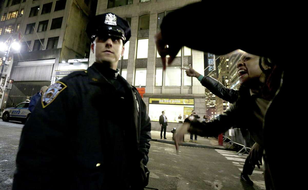 A woman, right, yells at a New York City Police officer during a protest after it was announced that the police officer involved in the death of Eric Garner is not being indicted, Wednesday, Dec. 3, 2014, in New York.