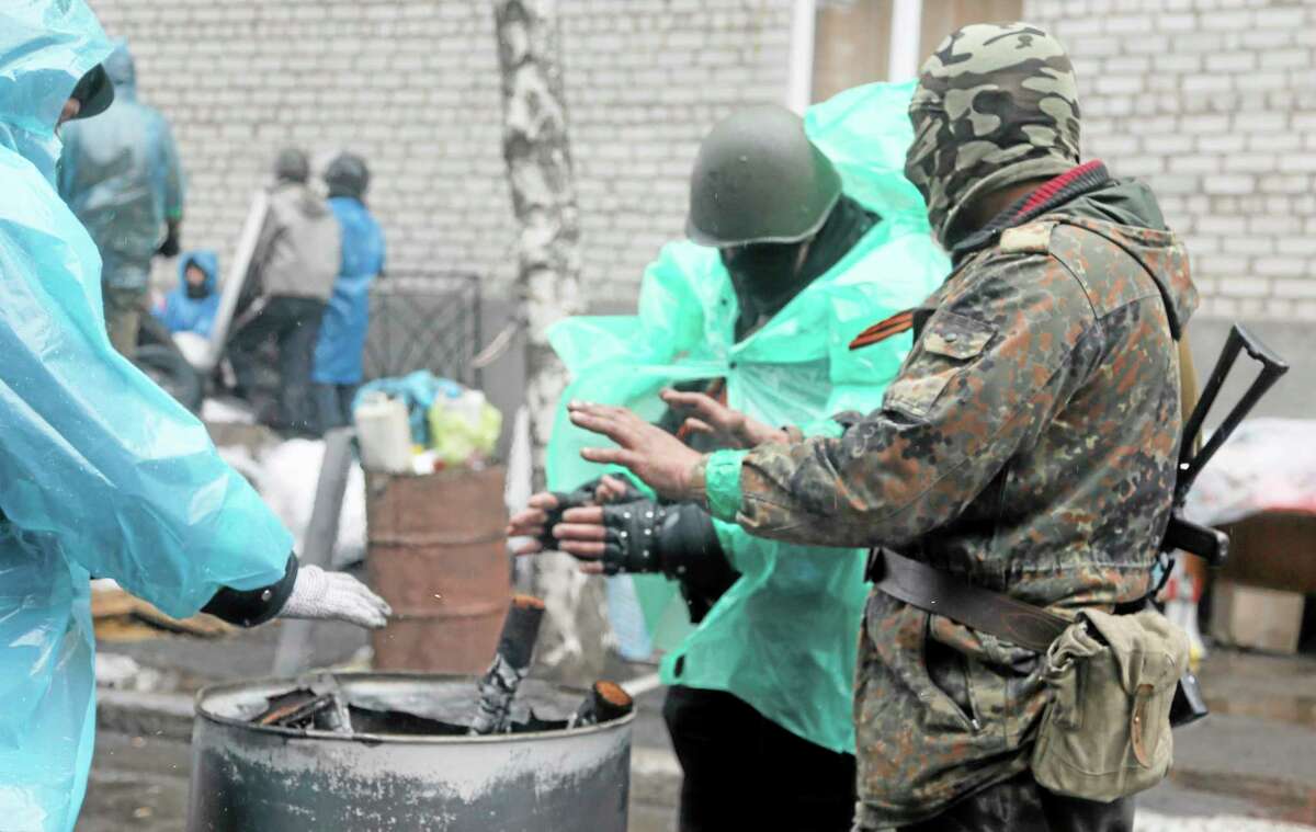 Pro-Russian gunmen warm themselves next to a bonfire as they guard a seized police station in the eastern Ukraine town of Slovyansk on April 13. (AP PHOTO/EFREM LUKATSKY)
