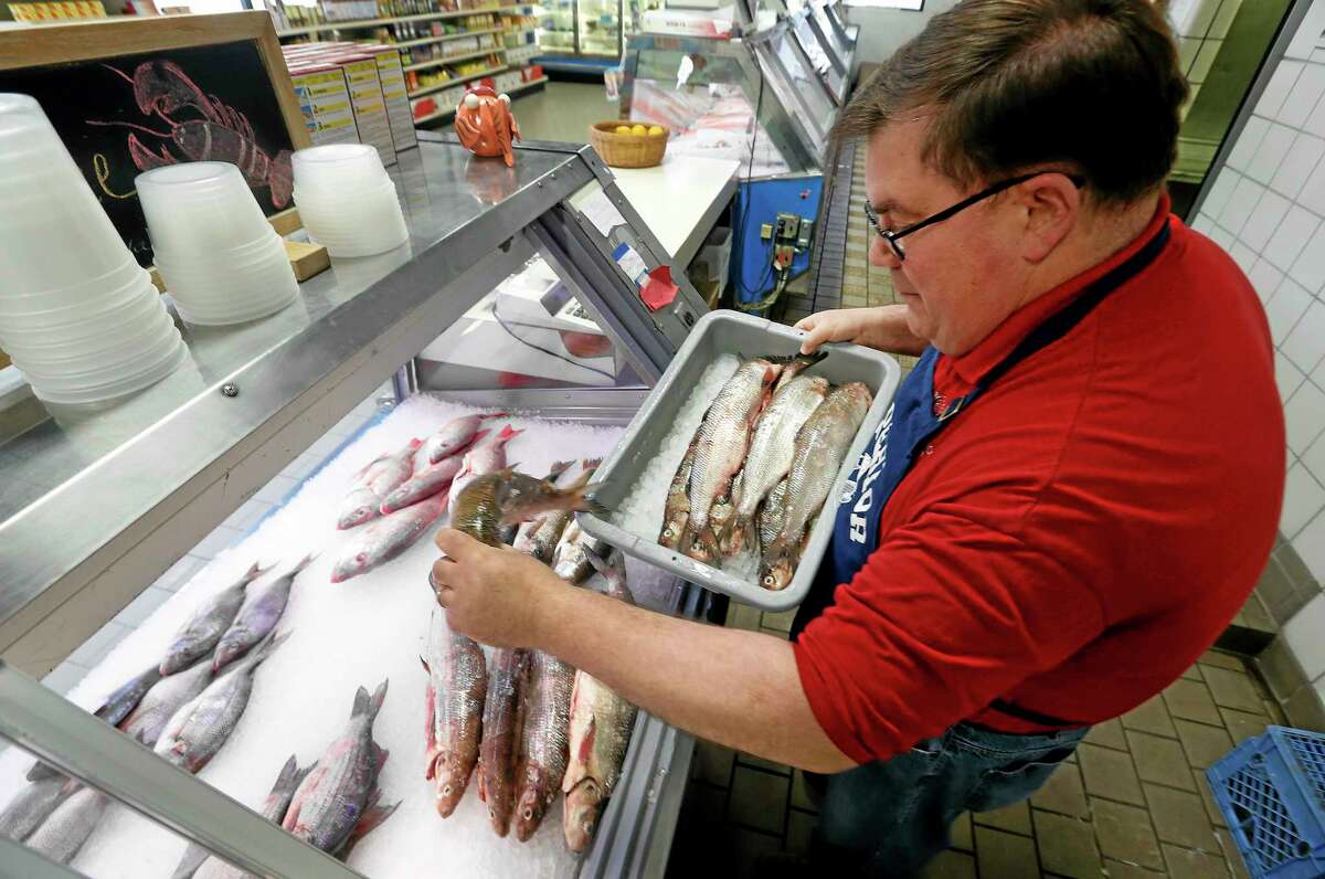 Kevin Dean, co-owner of Superior Fish Company, puts whitefish out for sale in Royal Oak, Mich., Monday.