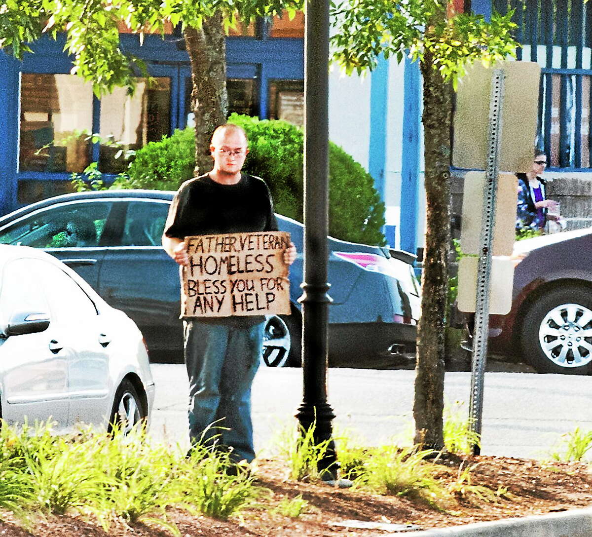 A man stands with a sign off the Post Road in Milford Friday