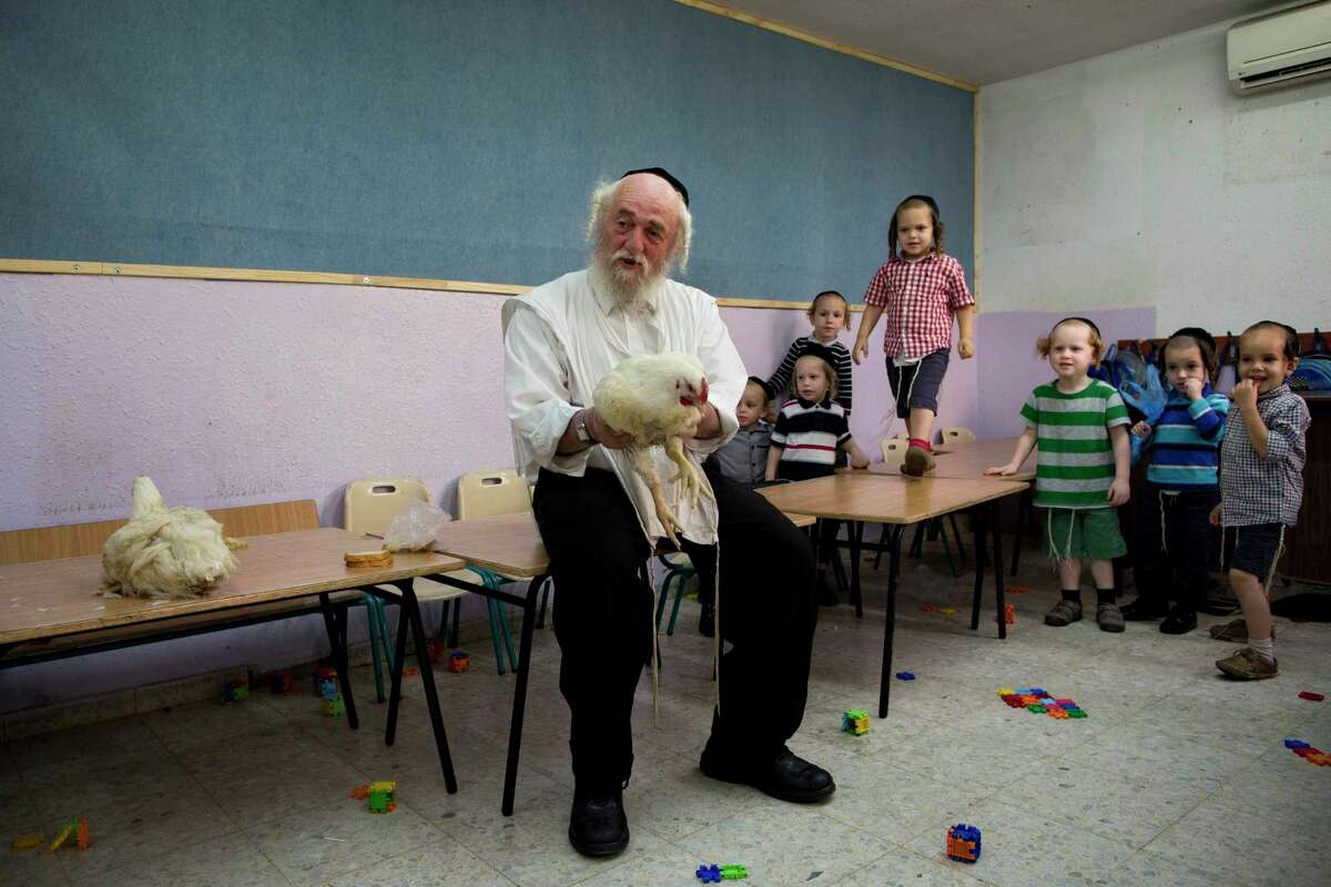 An ultra-Orthodox Jewish man holds a chicken as he talks to children Thursday about the Kaparot ritual in the city of Bnei Brak, near Tel Aviv, Israel. Observers believe the ritual transfers one’s sins from the past year into the chicken, and the ritual is performed before the Day of Atonement, Yom Kippur, the holiest day in the Jewish year, which starts at sundown Friday.