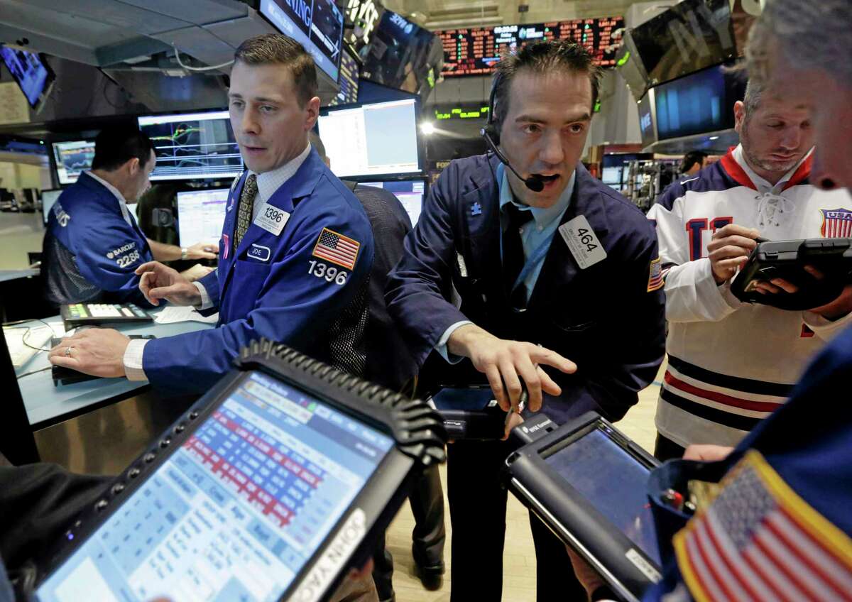 Trader Gregory Rowe, center, works at the post of specialist Joseph Mastrolia, left, on the floor of the New York Stock Exchange Friday.