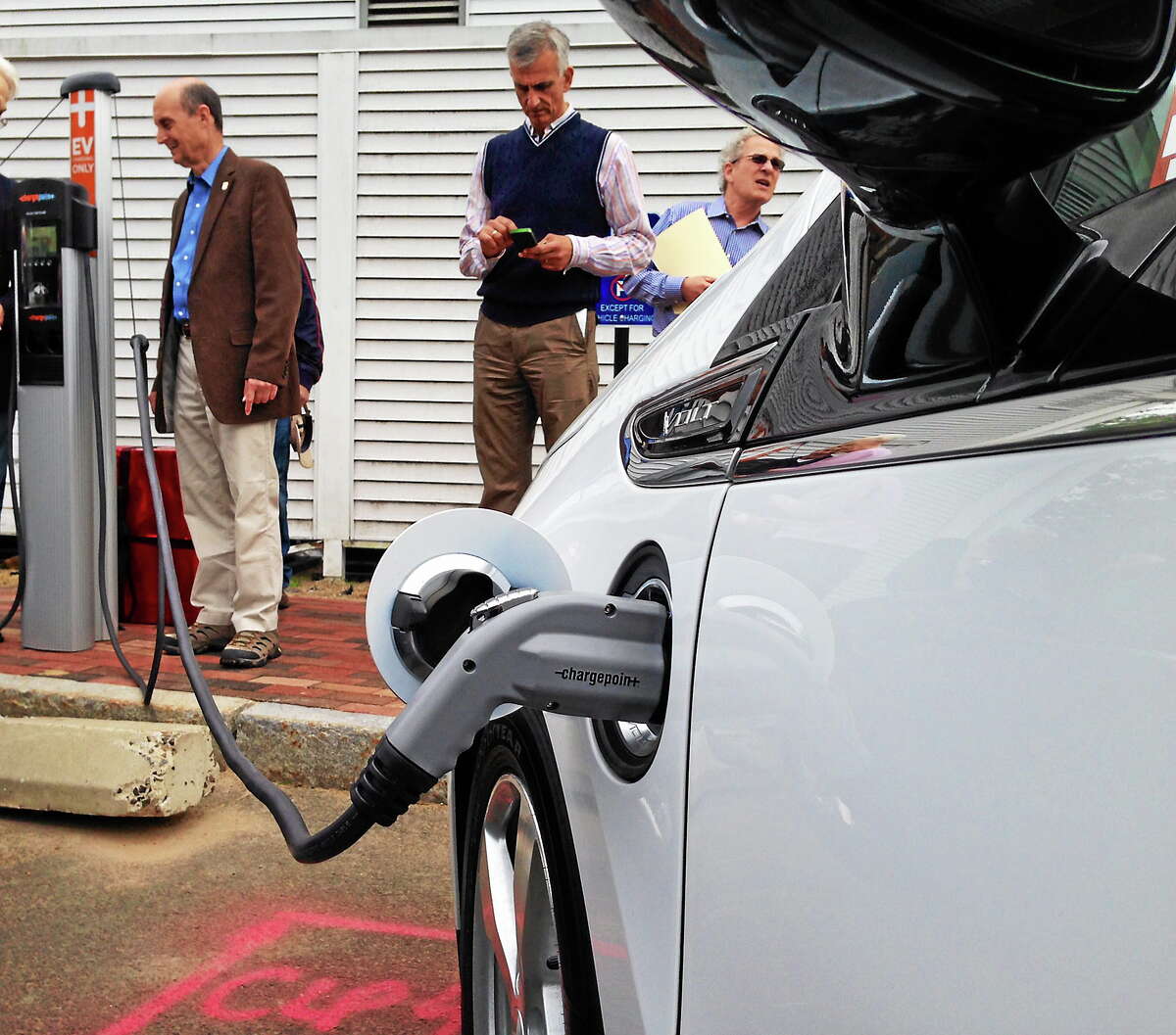 Madison officials demonstrate how the charging station works on a Chevy Volt.
