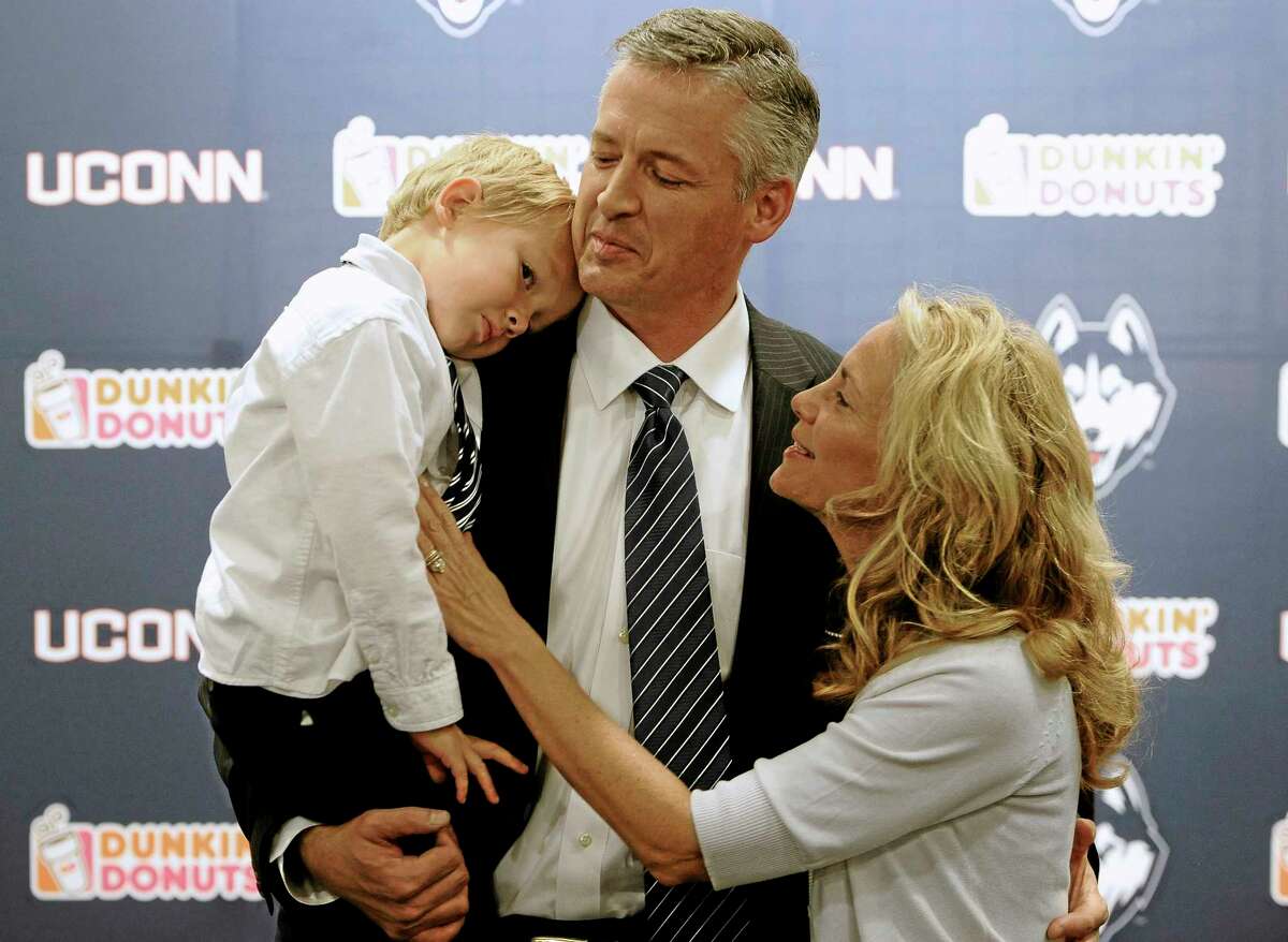 UConn interim head coach and former offensive coordinator T.J. Weist, center, holds his son James, left, as his wife Karen, right, watches, after a news conference Monday.