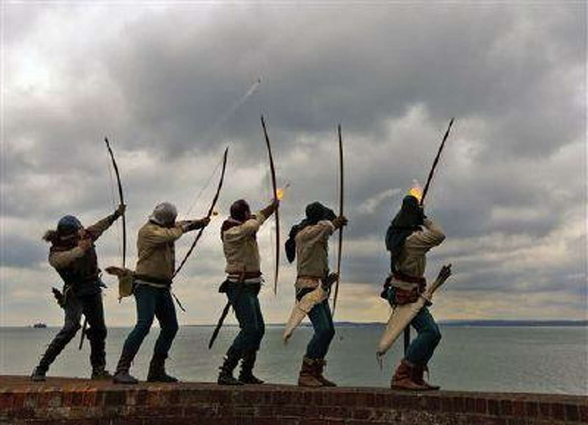 Archers of the Purbrook Bowmen, dressed in Tudor looking clothes, fire a volley of flaming arrows from Southsea Castle into The Solent, towards where the Mary Rose sank in 1545, at Portsmouth on the south coast of England, Thursday May 30, 2013. Henry VIII's flagship sank during a battle against the French navy and was raised from the seabed in 1982. The ceremony was one of the events to mark the opening of the new Mary Rose Museum at Portsmouth Historic Dockyard. In the background, left, is one of the Solent Forts, and at right is part of the Isle Of Wight. (AP Photo / Chris Ison, PA) UNITED KINGDOM OUT, NO SALES, NO ARCHIVE