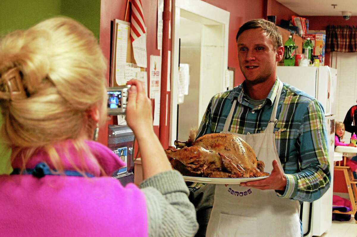 In this file photo, Deirdre Houlihan DiCara, executive director of Friends in Service to Humanity, takes a photo of Earl Gibson, case manager for families and individuals, while he holds a turkey during the FISH Family Thanksgiving Dinner  in Torrington. FISH helps provide shelter for people without homes.